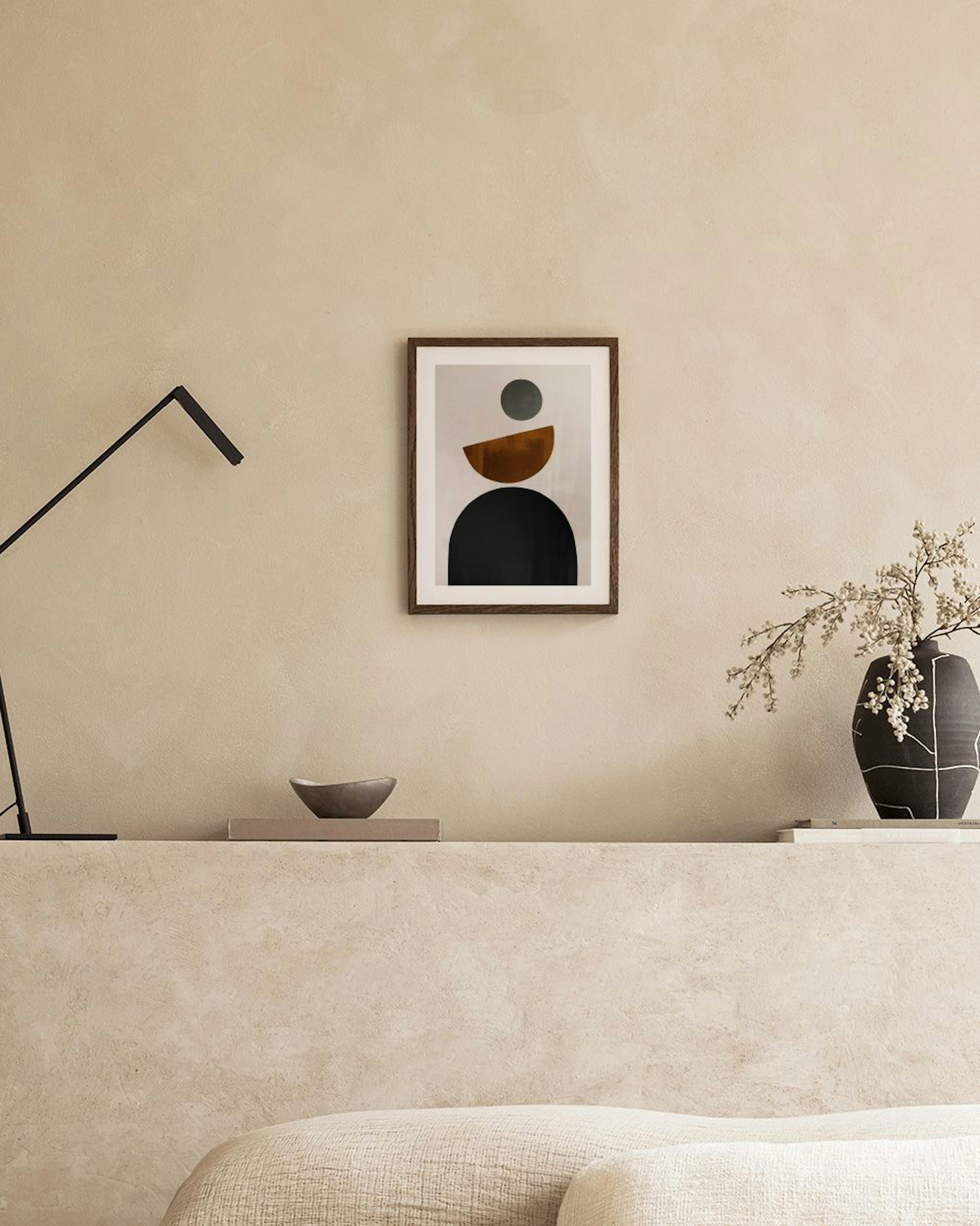 Abstract print with black arch, brown semicircle, and grey circle on a light background, hanging above a brown ottoman.