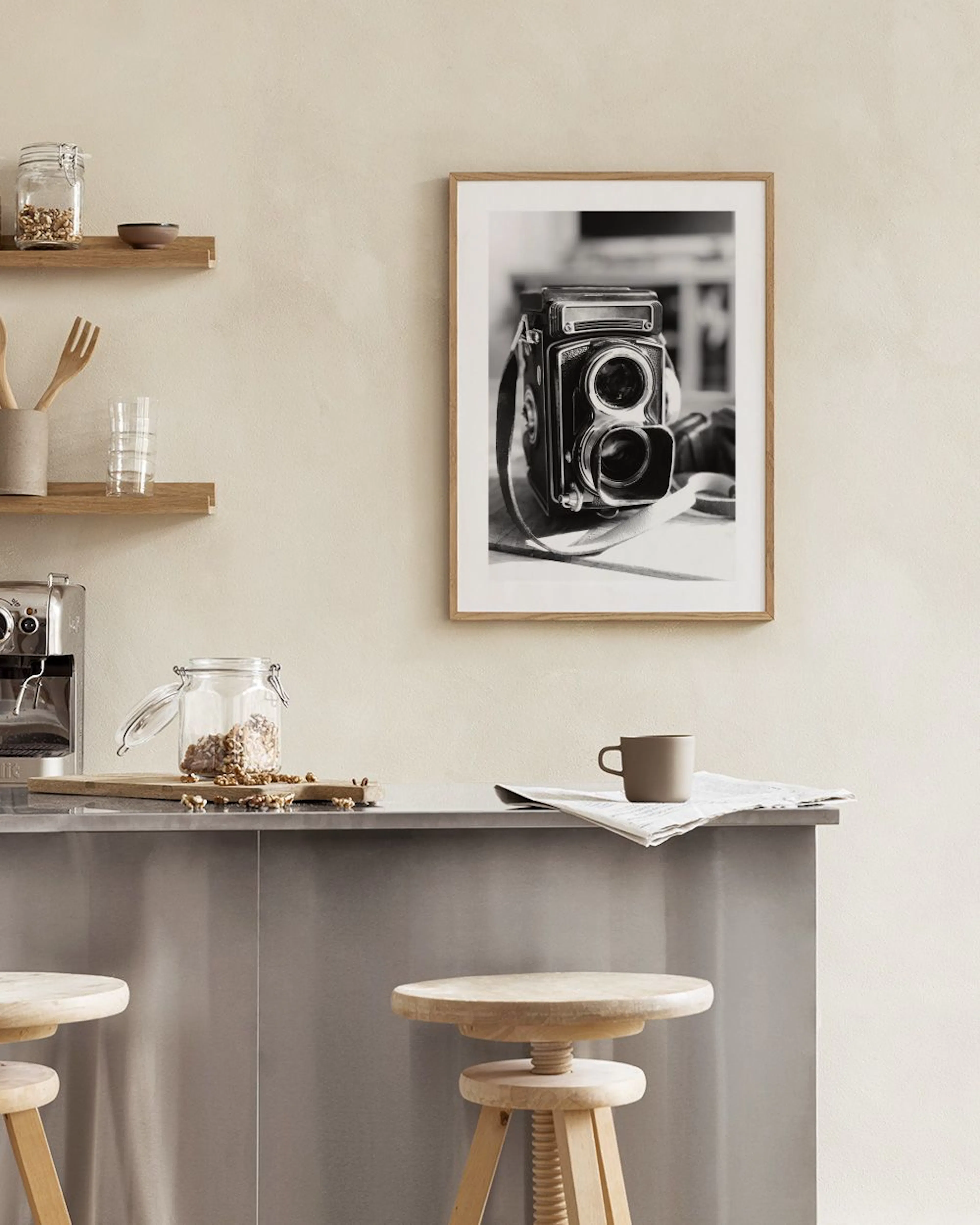 Affiche en noir et blanc dun appareil photo vintage, accrochée dans une pièce lumineuse avec un fauteuil et des éléments décorat