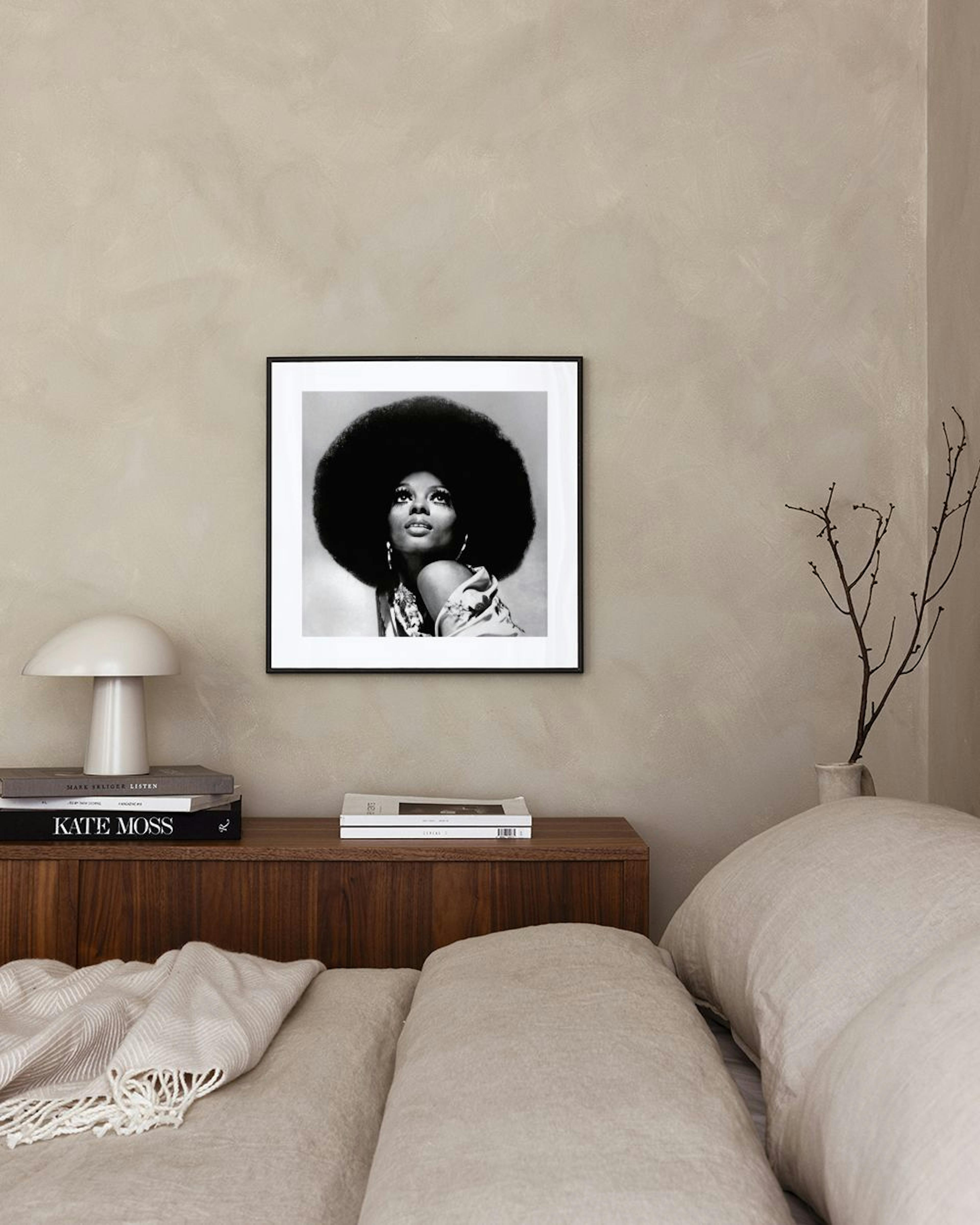Affiche en noir et blanc dune femme avec une coiffure afro, accrochée au-dessus dun fauteuil dans un salon.