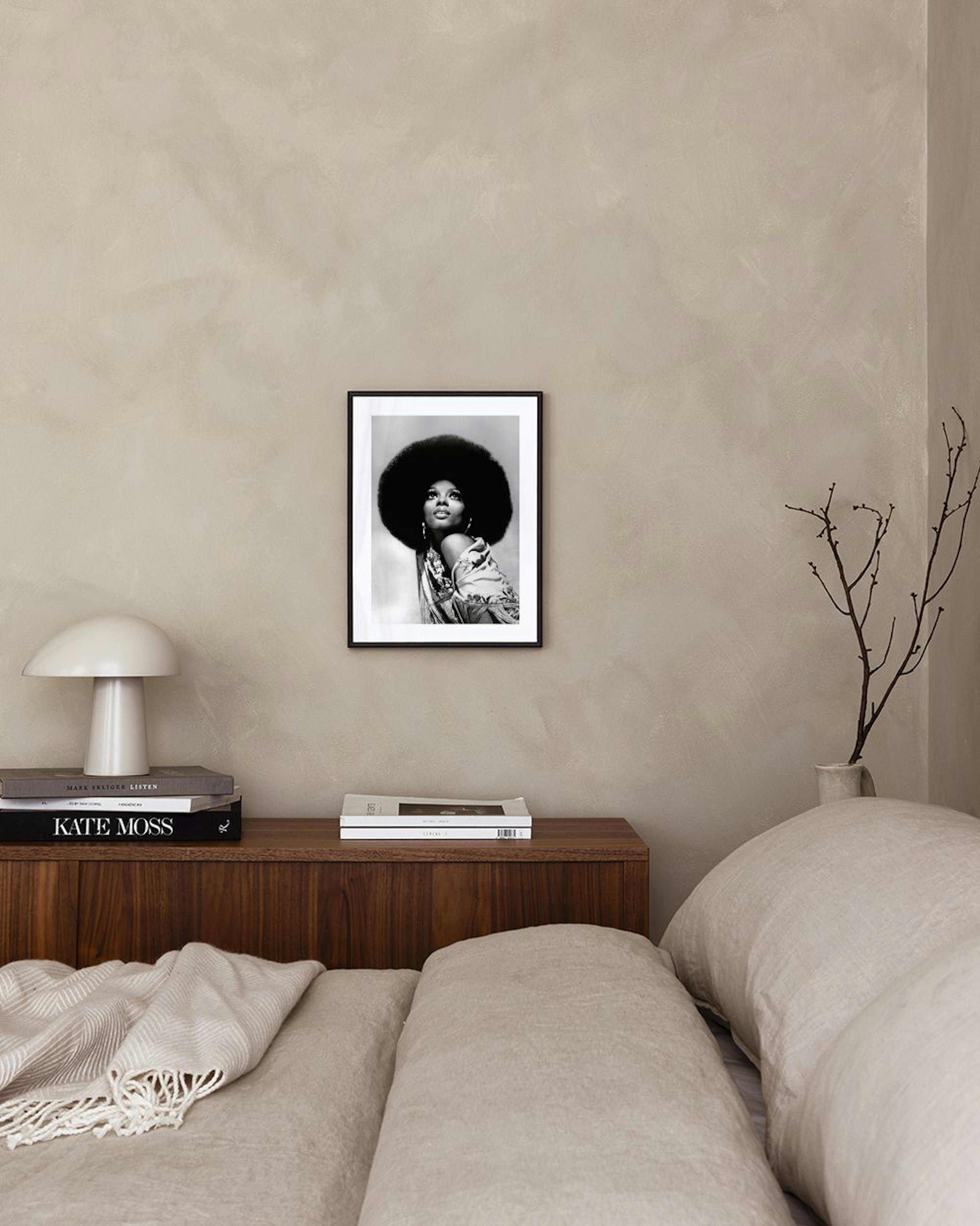 Poster in bianco e nero di una donna con acconciatura afro, appeso in un soggiorno moderno sopra una poltrona beige.