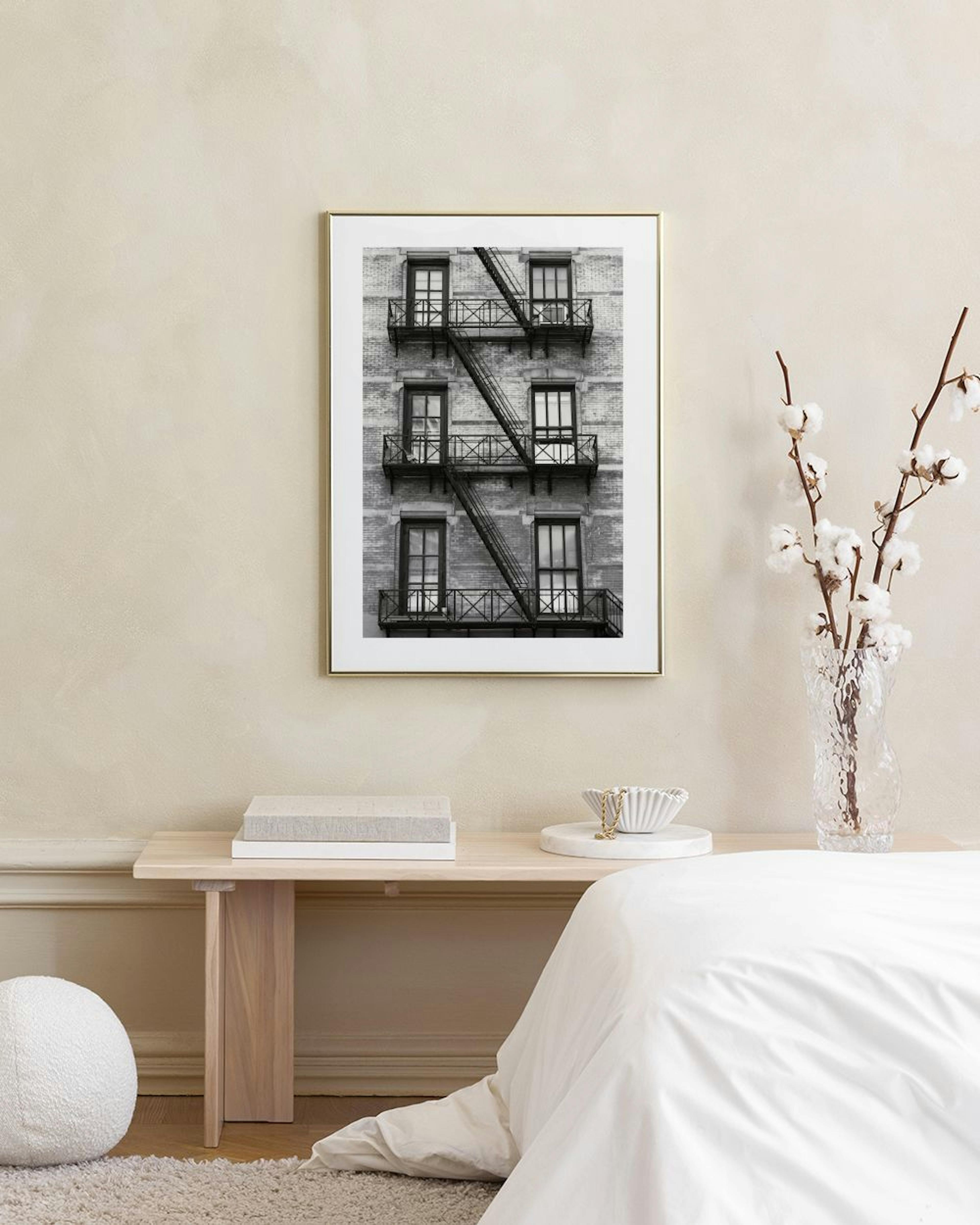 Affiche en noir et blanc dune façade de bâtiment avec escalier de secours, suspendue au-dessus dune table basse avec des objets 