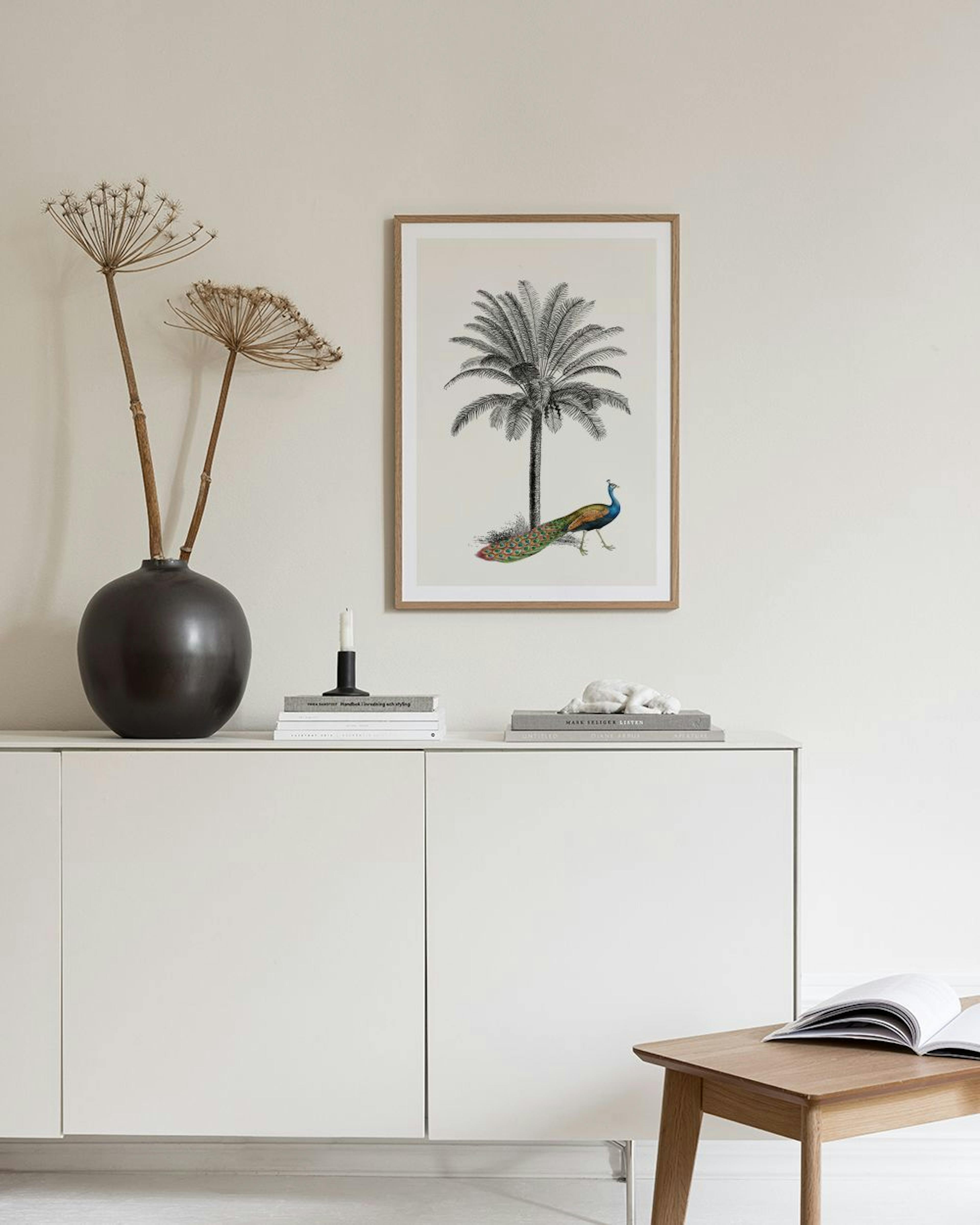 A poster of a palm tree illustration with a colorful peacock, hanging above a side table in a room with a blue velvet chair.