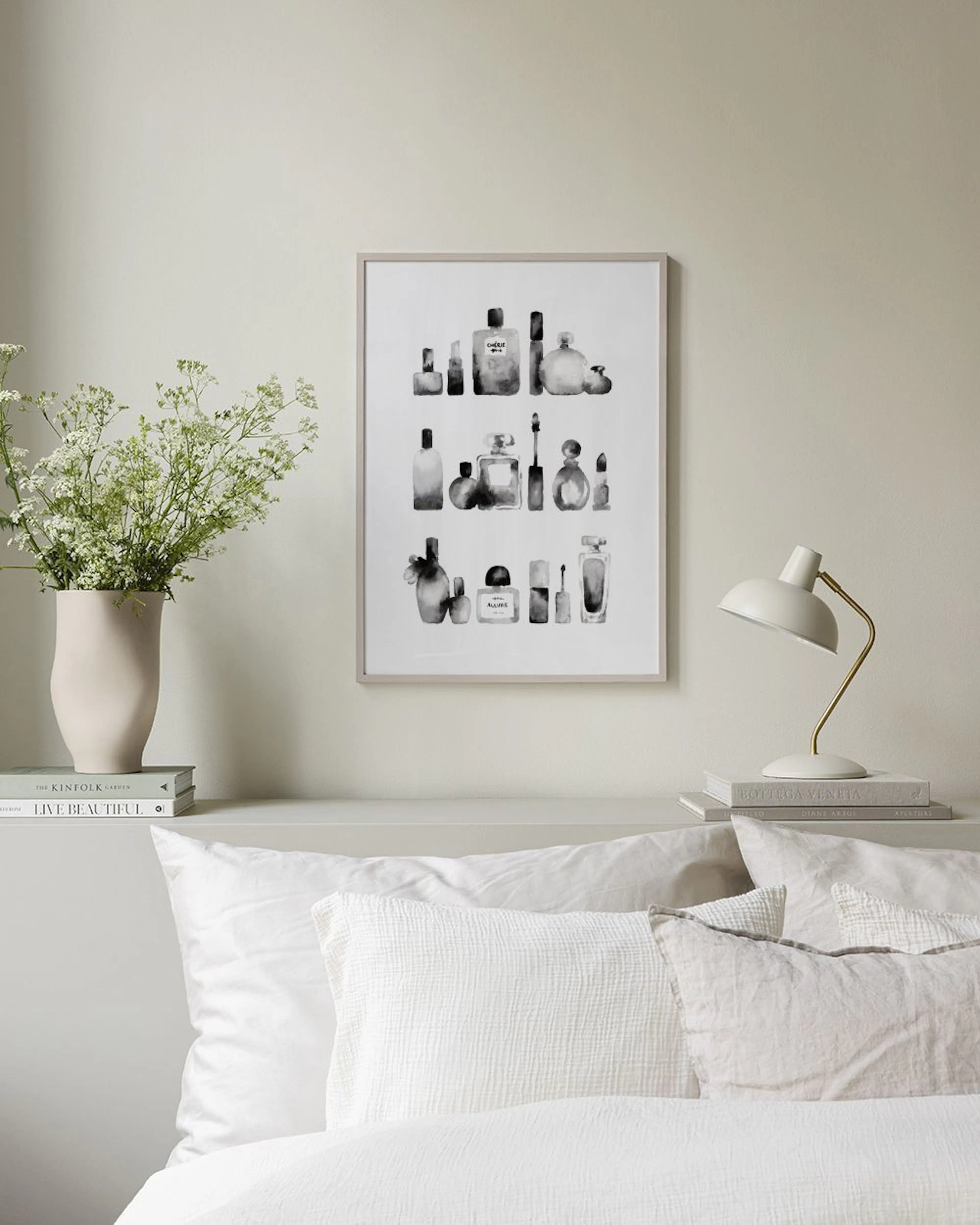 Póster minimalista de frascos de perfume y cosméticos en blanco y negro, sobre un mueble blanco con un jarrón y un libro.