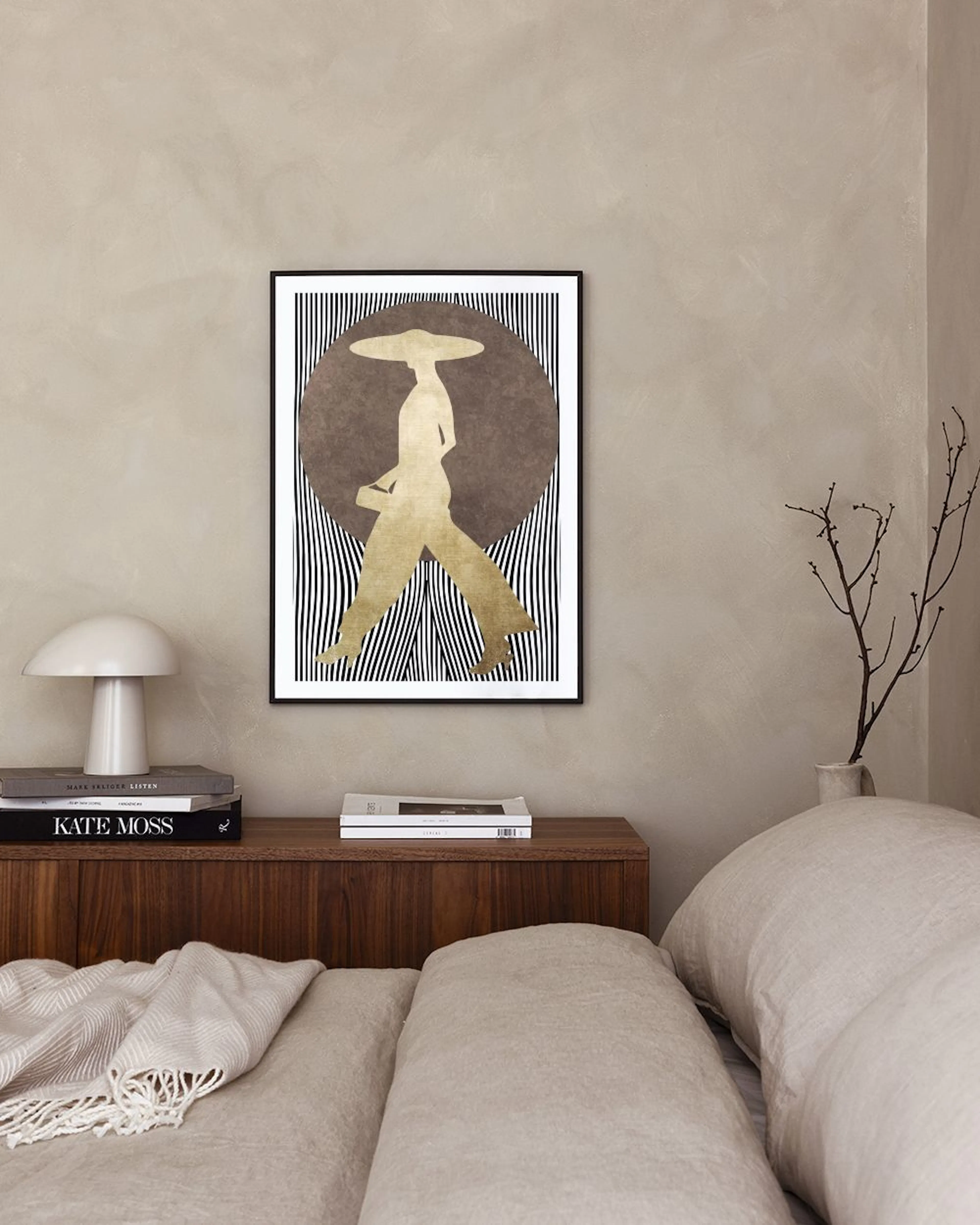 Poster con silhouette dorata di donna con cappello, su sfondo marrone e linee bianche e nere, appeso sopra una credenza grigia.