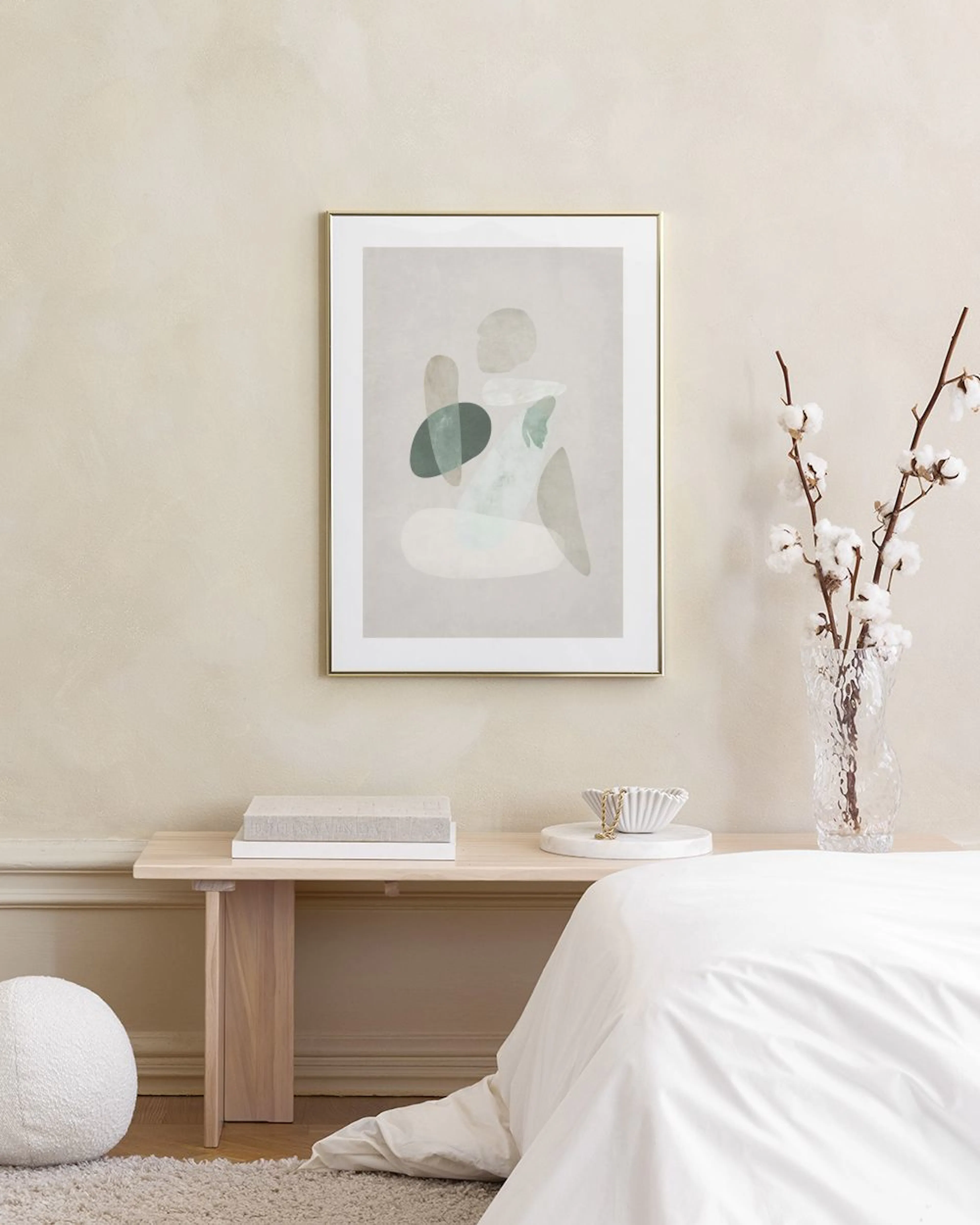 Affiche abstraite aux formes organiques vertes, beiges et blanches, accrochée au-dessus dun fauteuil vert.