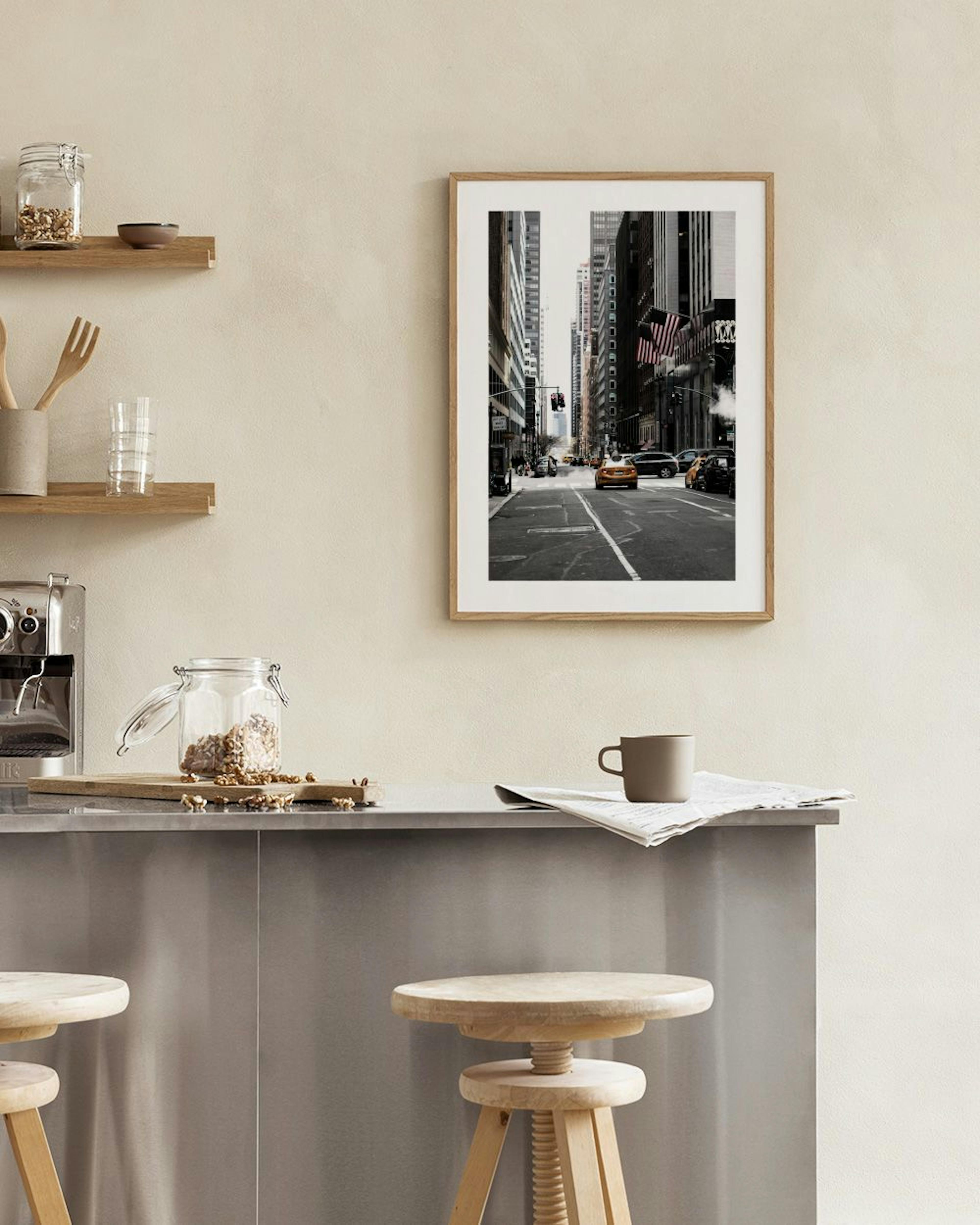 Un póster de una calle de Nueva York con taxis amarillos en blanco y negro, colgado en una pared gris sobre un mueble de madera.