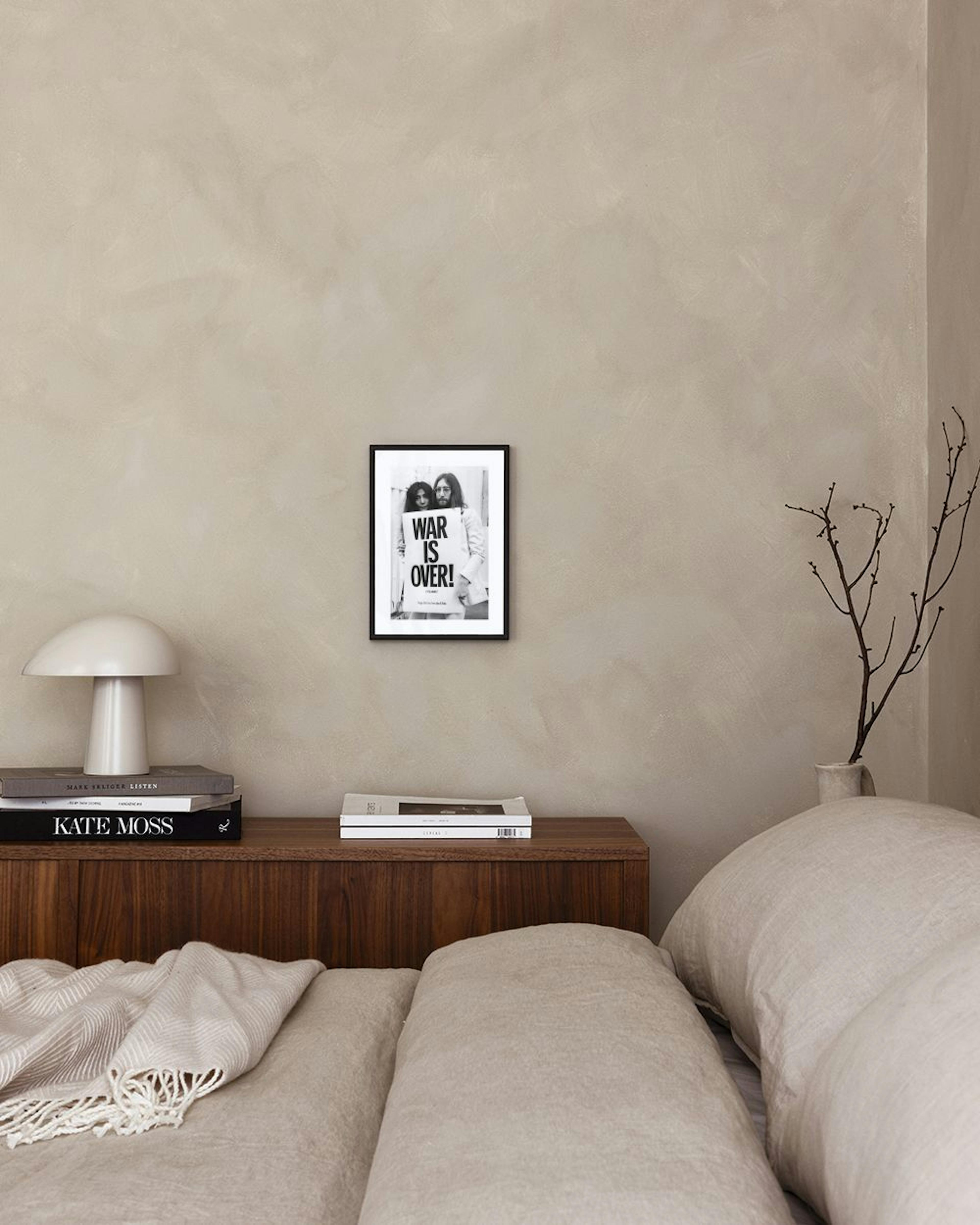 Affiche noir et blanc de John Lennon et Yoko Ono tenant une pancarte WAR IS OVER !, accrochée au-dessus dune étagère blanche et 