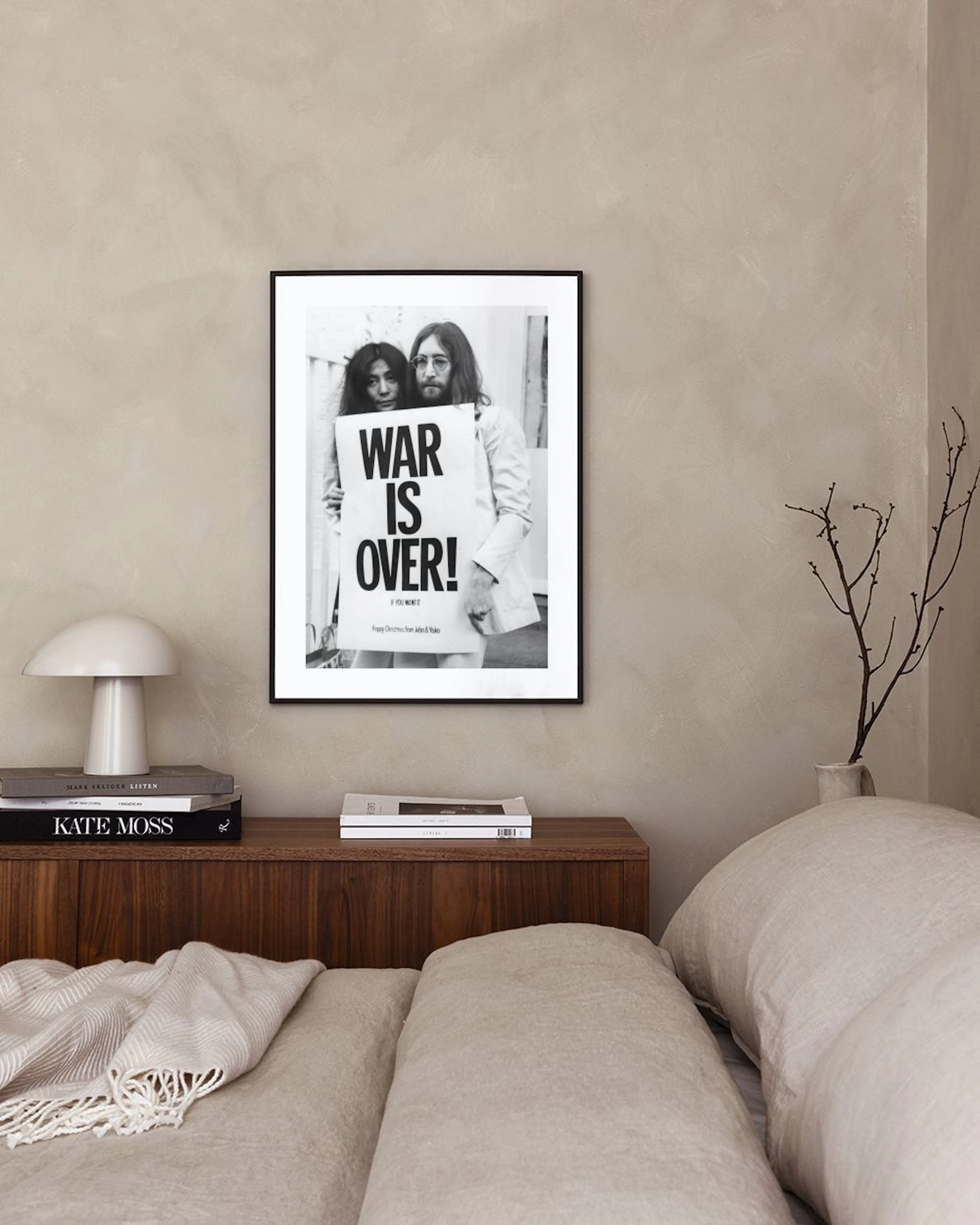 Čiernobiely plagát Johna Lennona a Yoko Ono s nápisom WAR IS OVER!“ v modernom interiéri.