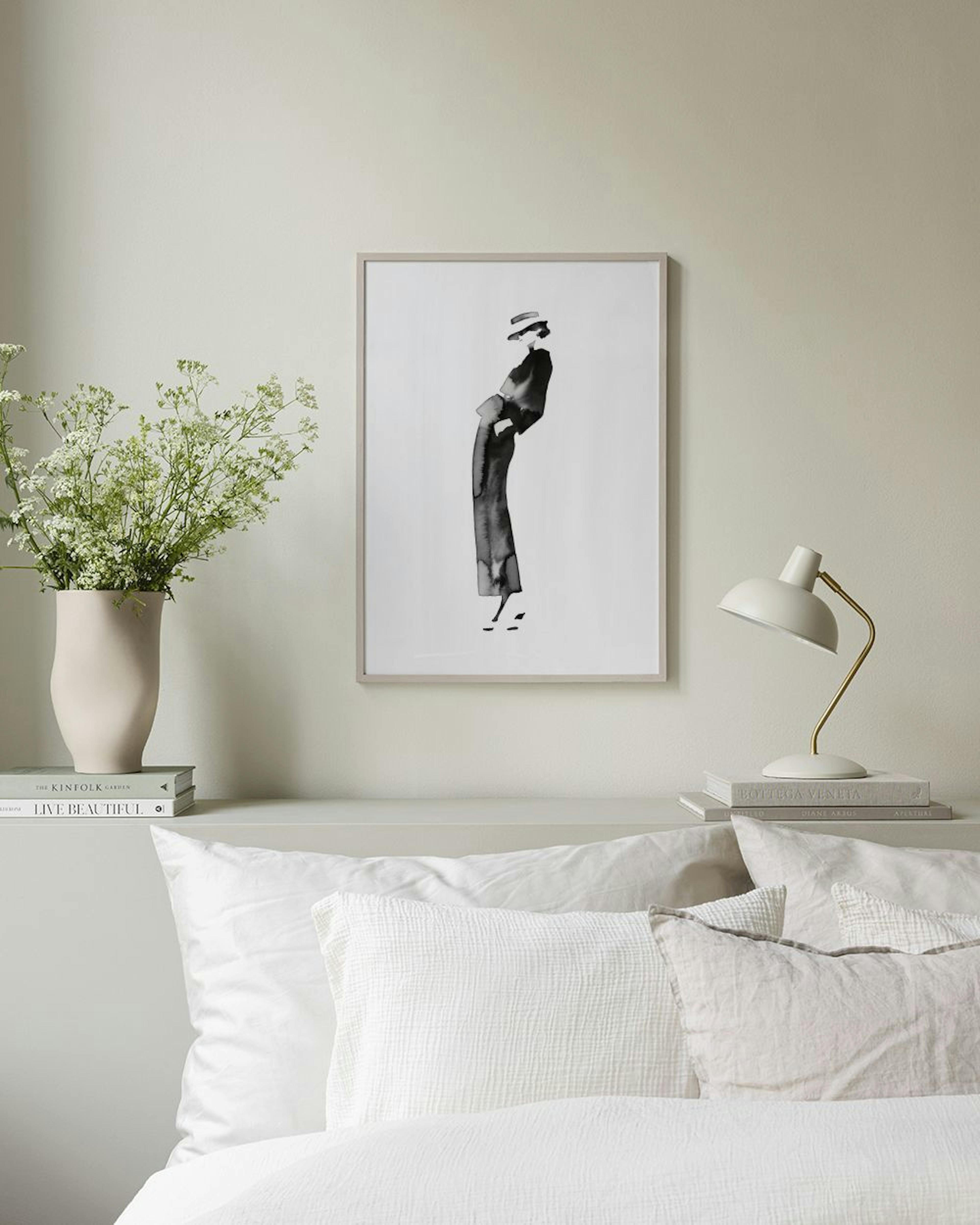A fashion illustration print of a woman in a hat and long dress, hanging above a black shelf with books and decor.