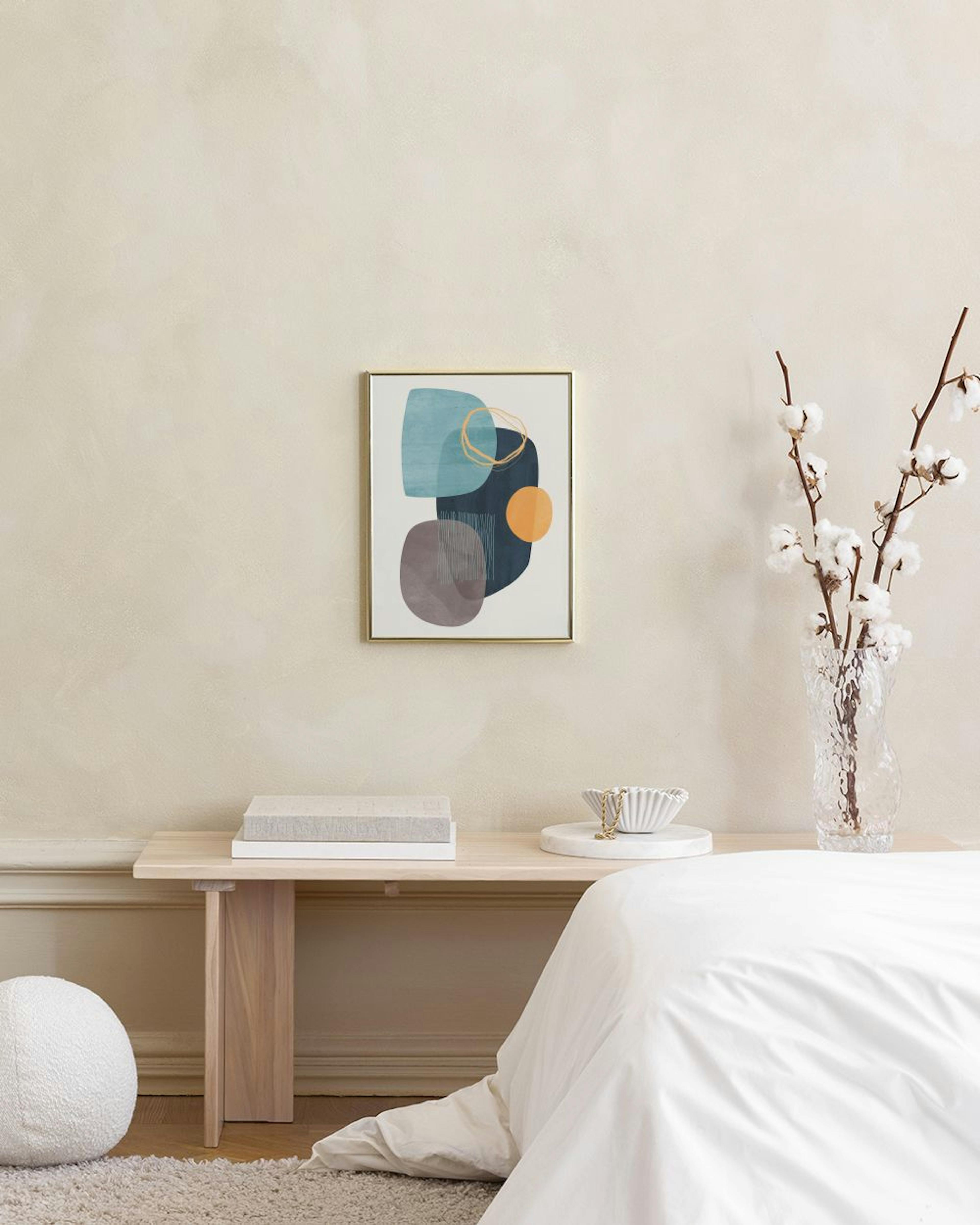 Poster com formas orgânicas azuis, castanhas e laranjas, círculos e linhas, pendurado acima de um móvel branco com livros e um v