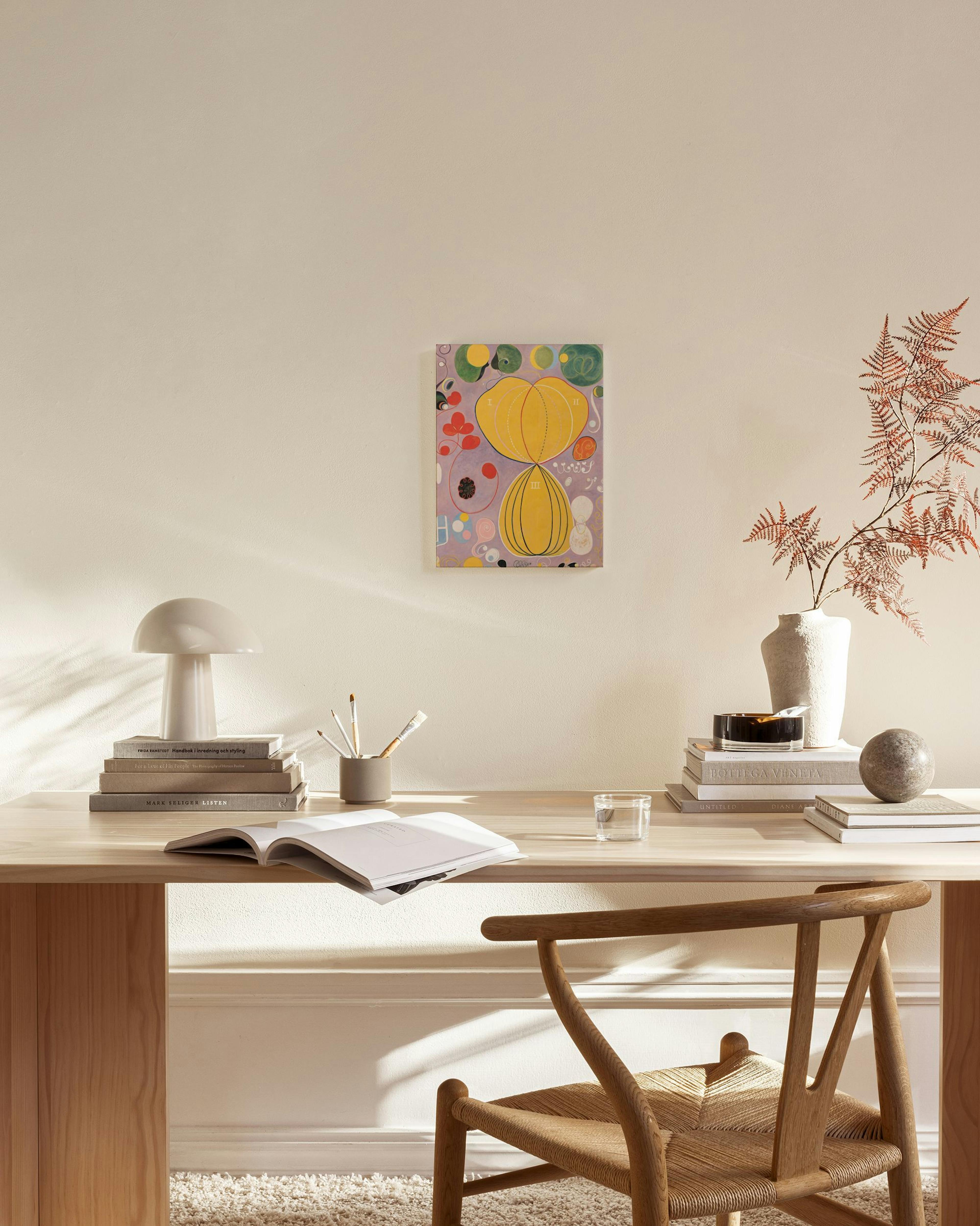 Toile abstraite aux formes jaunes et organiques rouges et vertes sur fond lilas, accrochée dans un salon scandinave épuré.