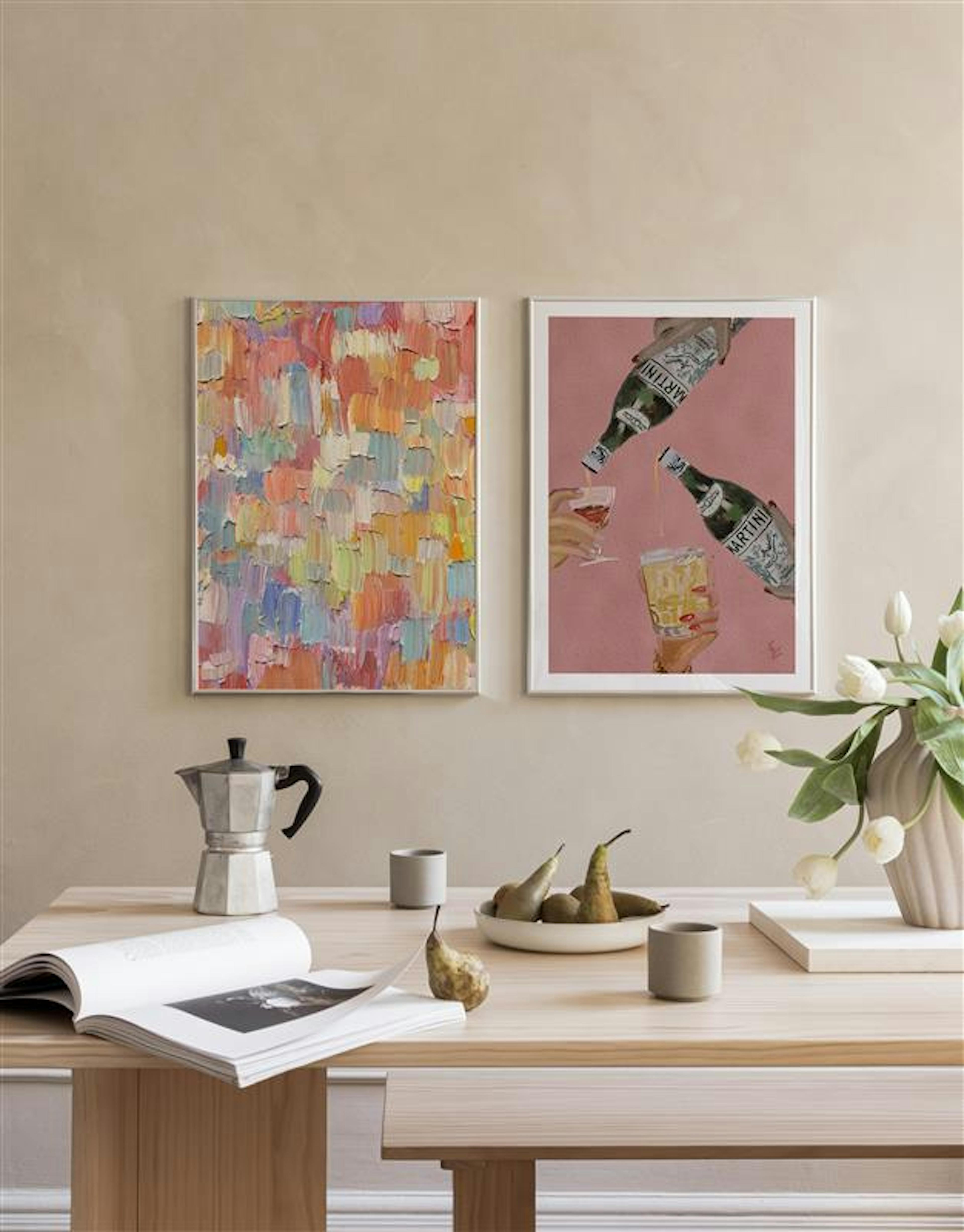 Dos pósters en una pared beige, uno con happy hour en naranja, otro con copas de cóctel y una figura, sobre una mesa de madera.
