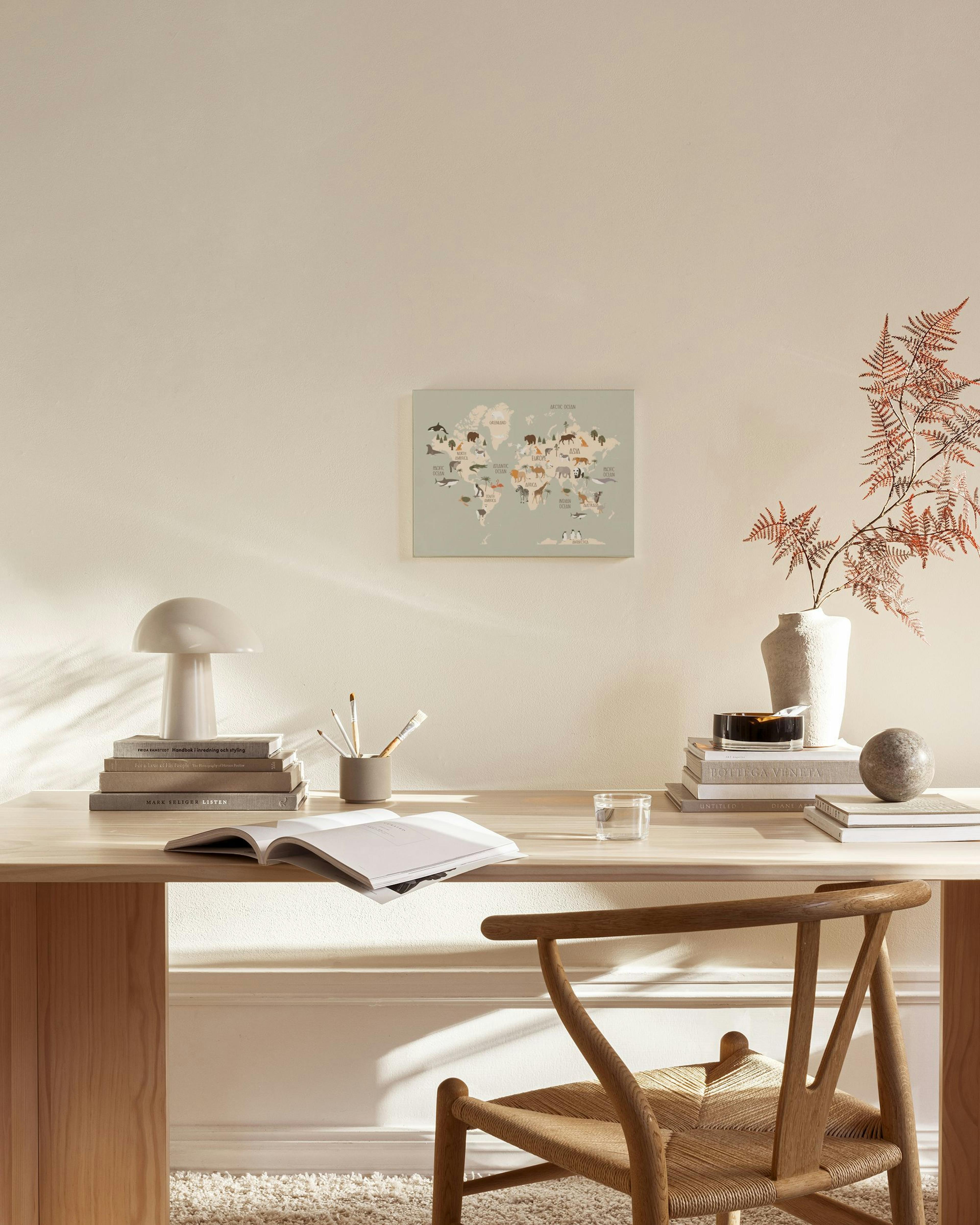 Tela decorativa de mapa-mundo com animais, pendurada em sala de estar moderna com móveis de madeira e mesa de centro de vidro.