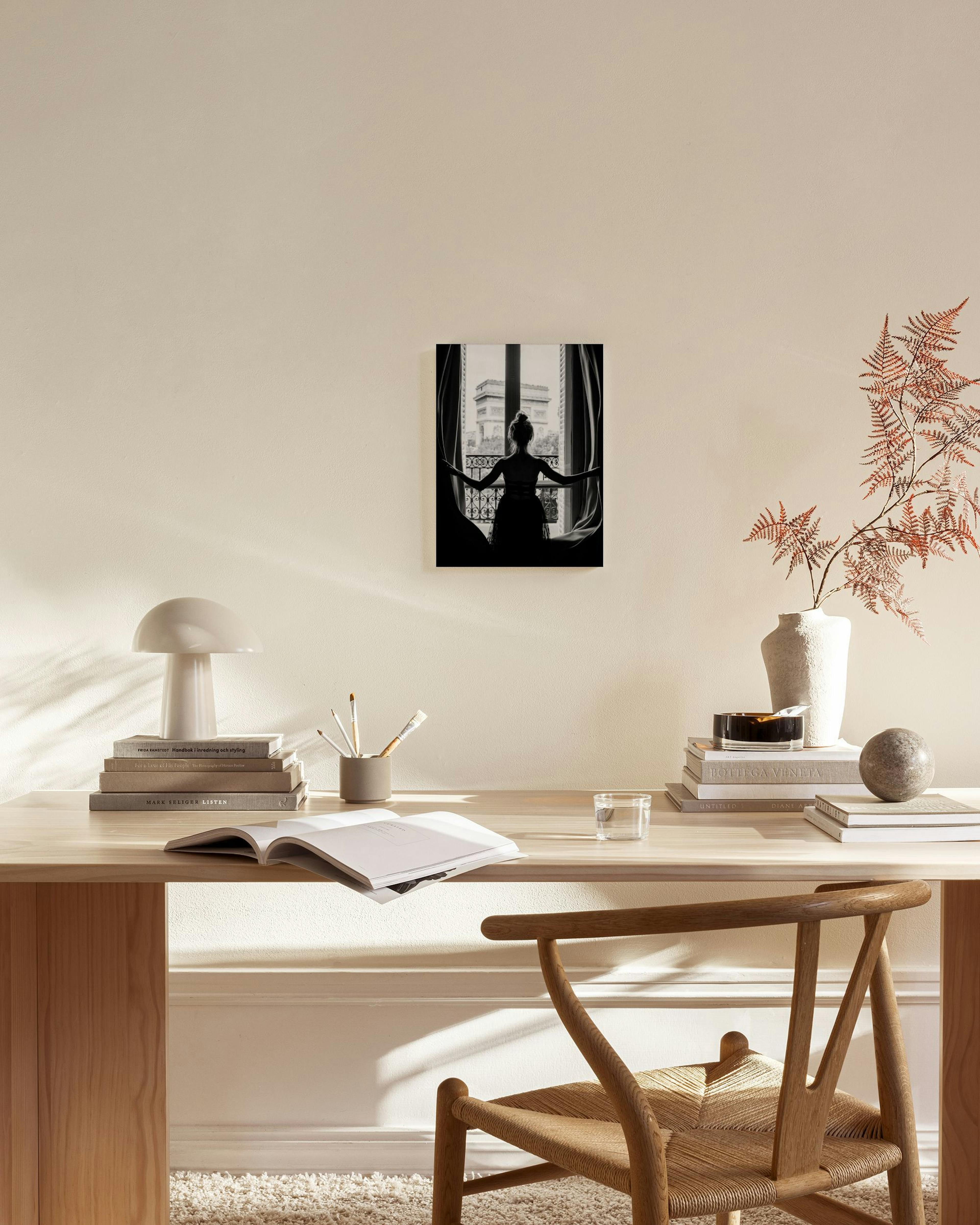 Zwart-wit canvas van een vrouw die uitkijkt op de Arc de Triomphe, hangend in een lichte woonkamer.