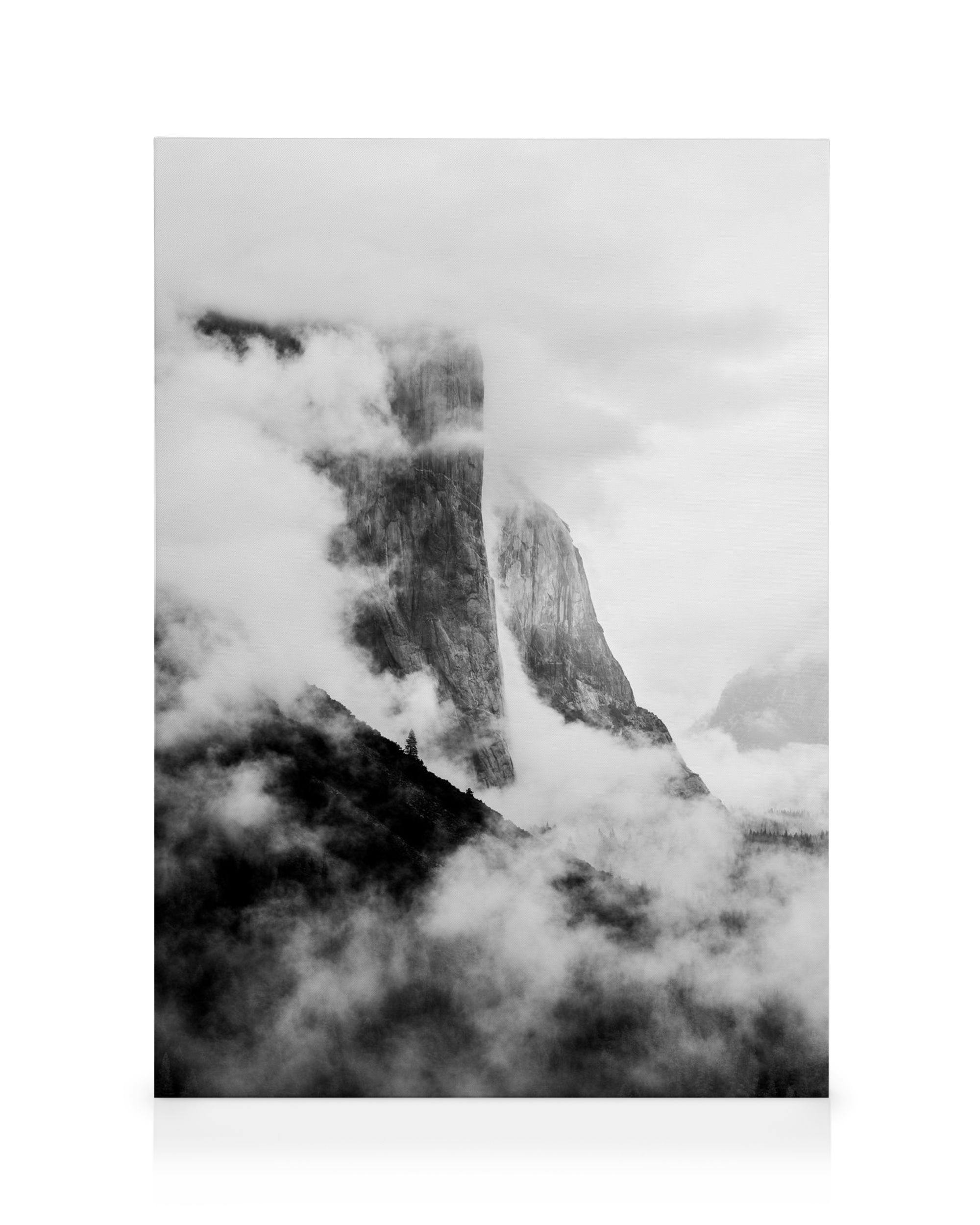 Monochromatic canvas print of El Capitan, a majestic mountain peak, shrouded in thick clouds.