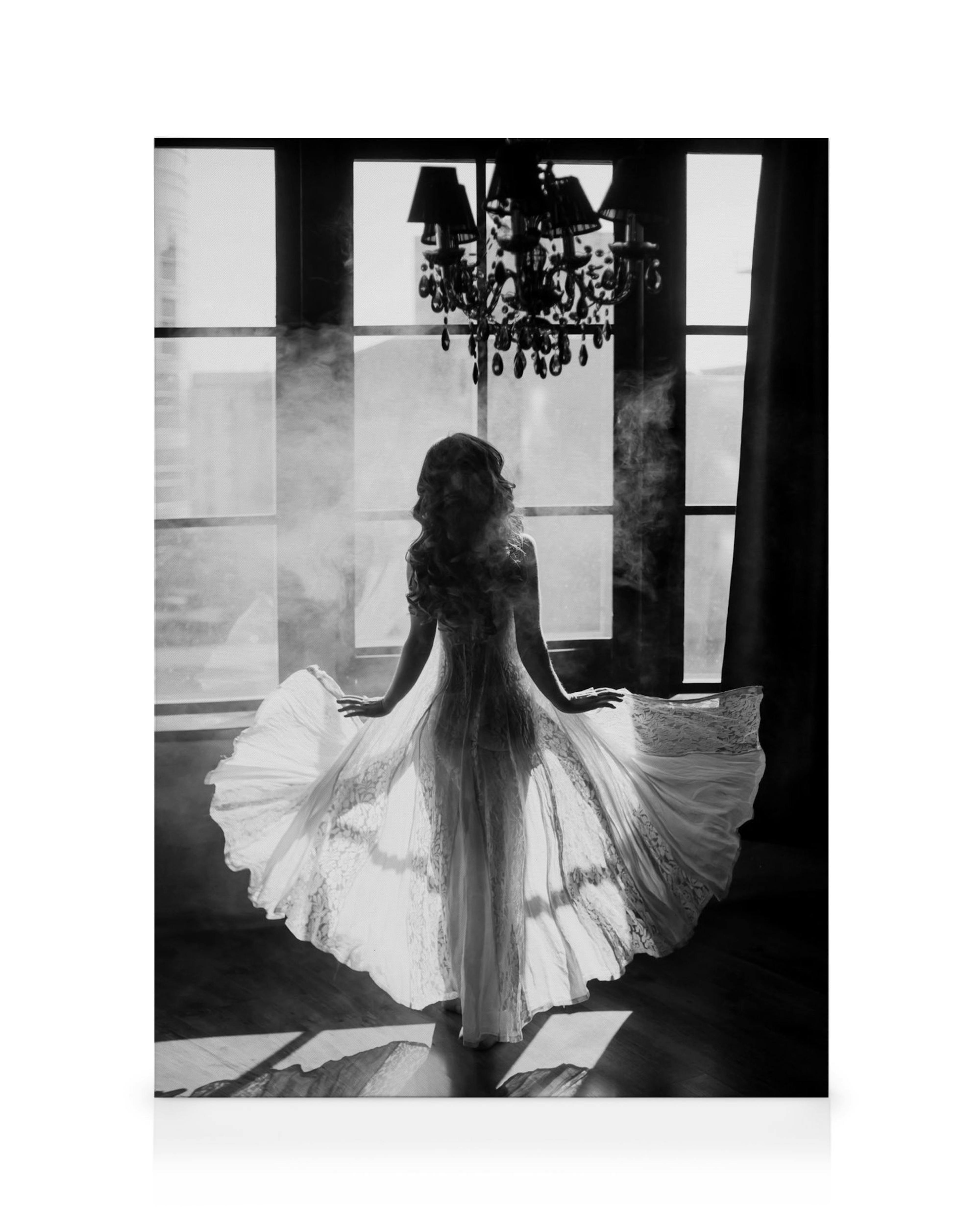 Black and white art print of a woman in a flowing white dress with a lace train, facing a window with a chandelier.