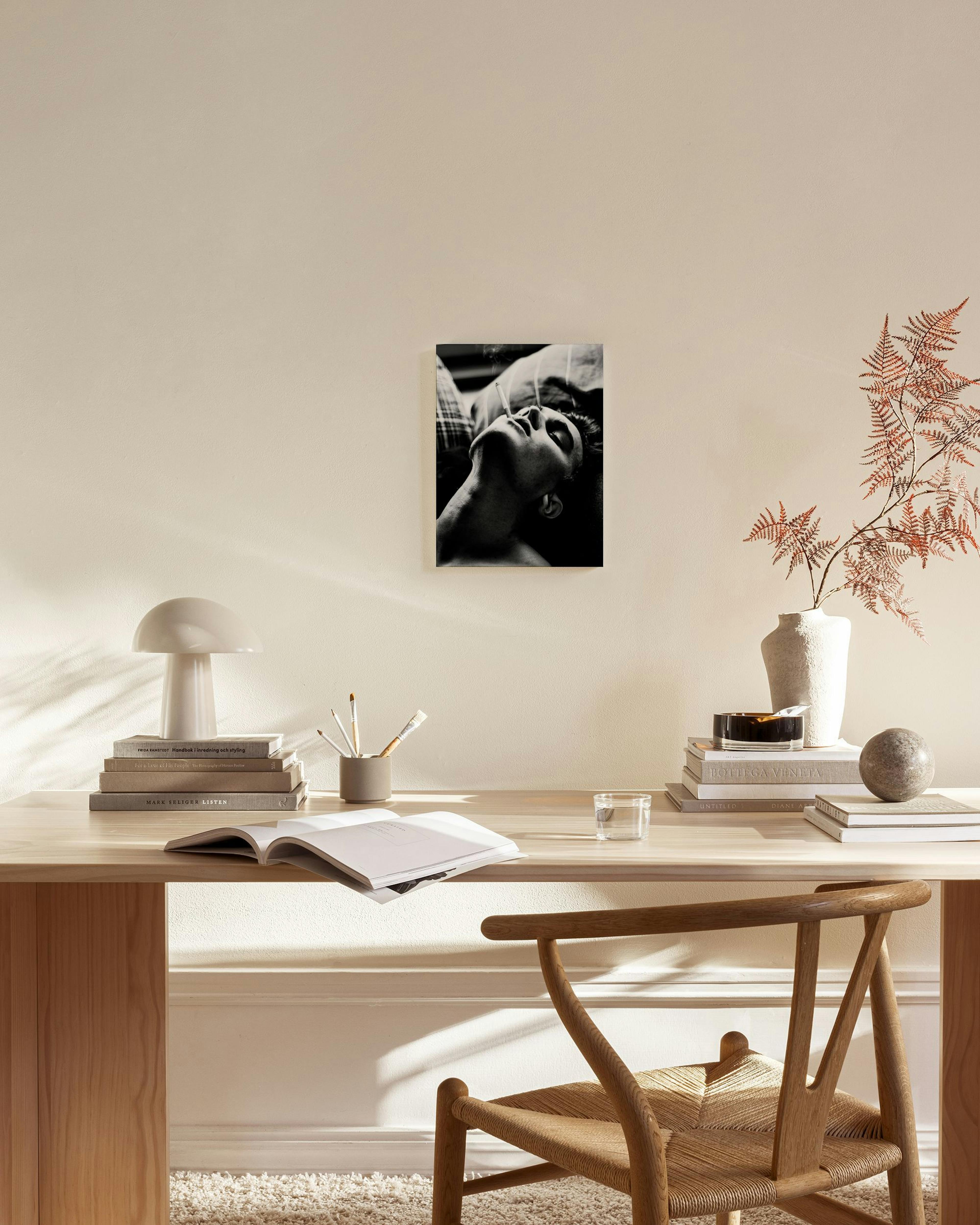 Toile noir et blanc dun homme qui fume, accrochée au-dessus dun banc en bois dans un salon moderne.