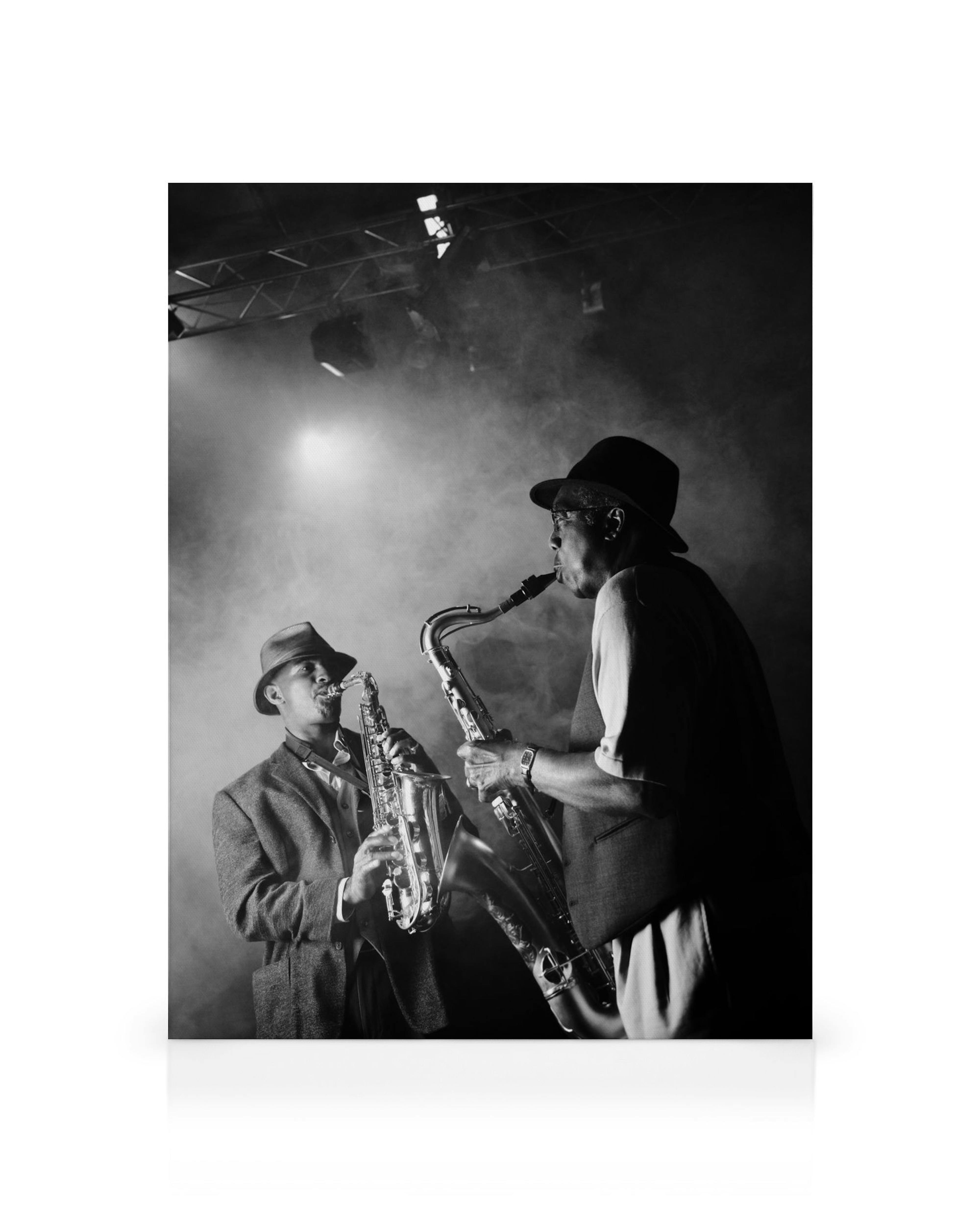Black and white jazz club canvas of two men in fedoras playing saxophones on a smoky stage with spotlights.
