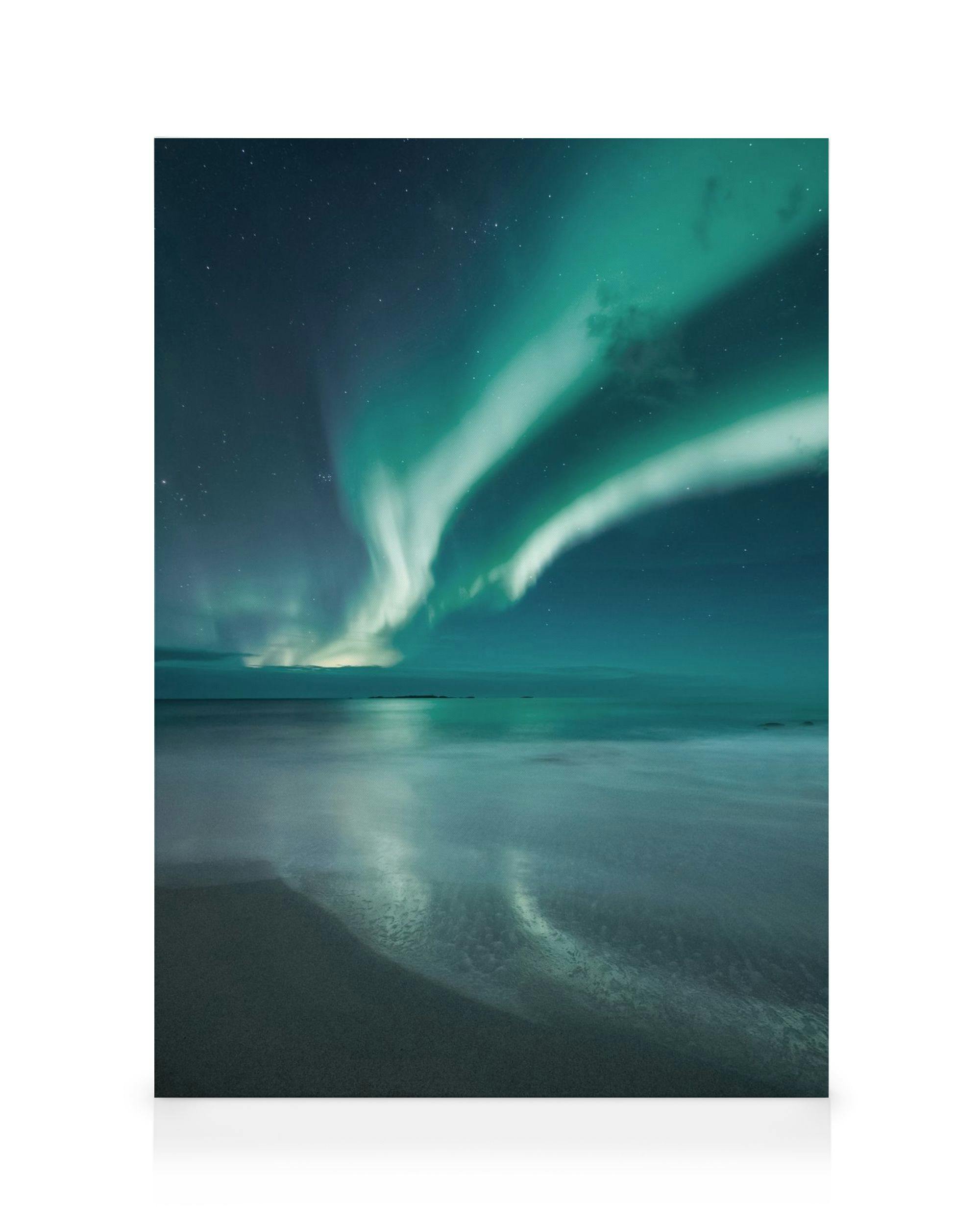 Lerret med grønt og turkis nordlys over mørkeblå himmel, speilet i hav og strand, skaper magisk stemning.