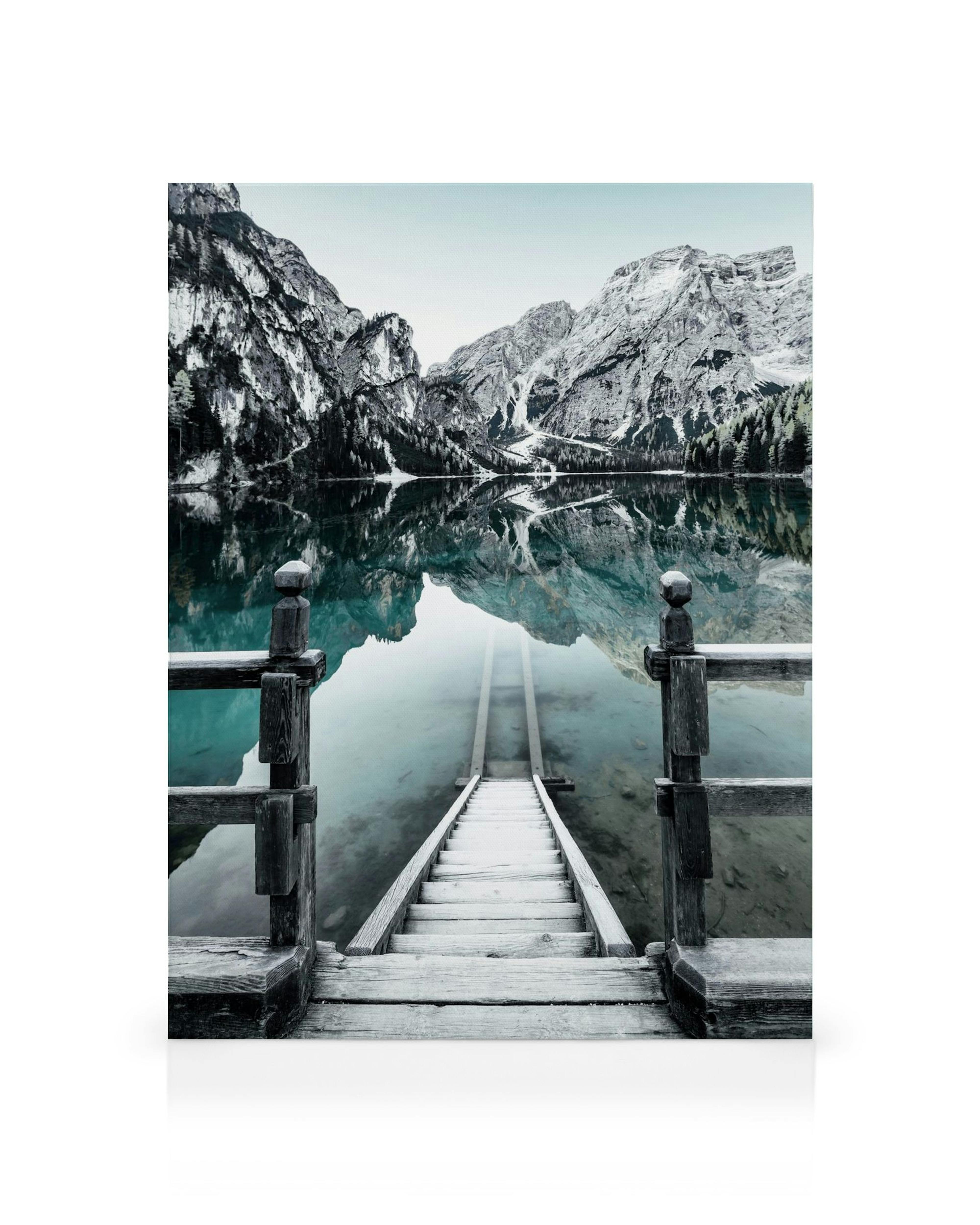 Braies-järven kanvaasitaulu, jossa puinen laituri johtaa veteen, vuoret heijastuvat tyyneen pintaan. Valokuvaus taide.
