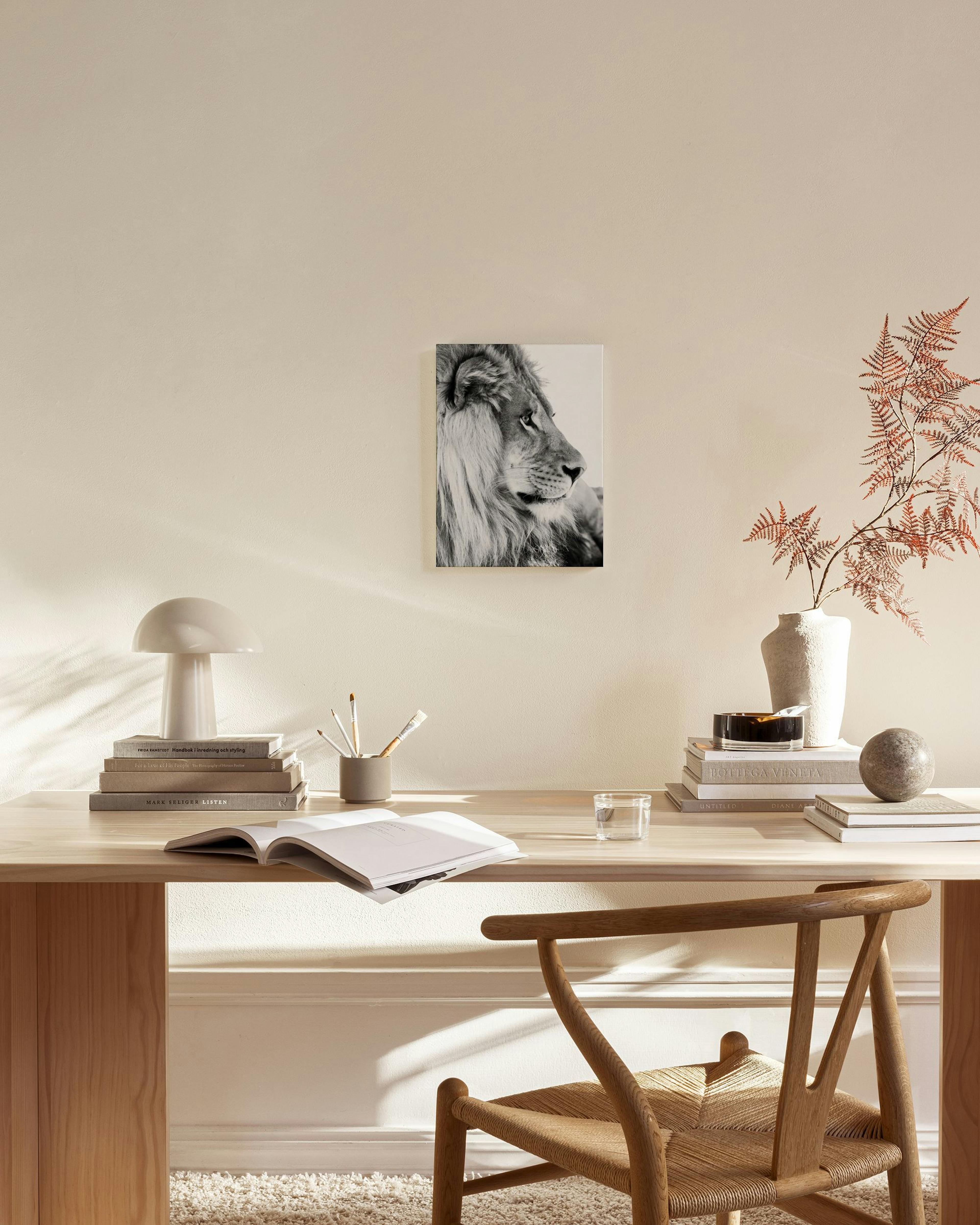 Schwarz-weißes Leinwandbild eines Löwenkopfes im Profil, hängend über einem hellen Sideboard in einem modernen Wohnzimmer.