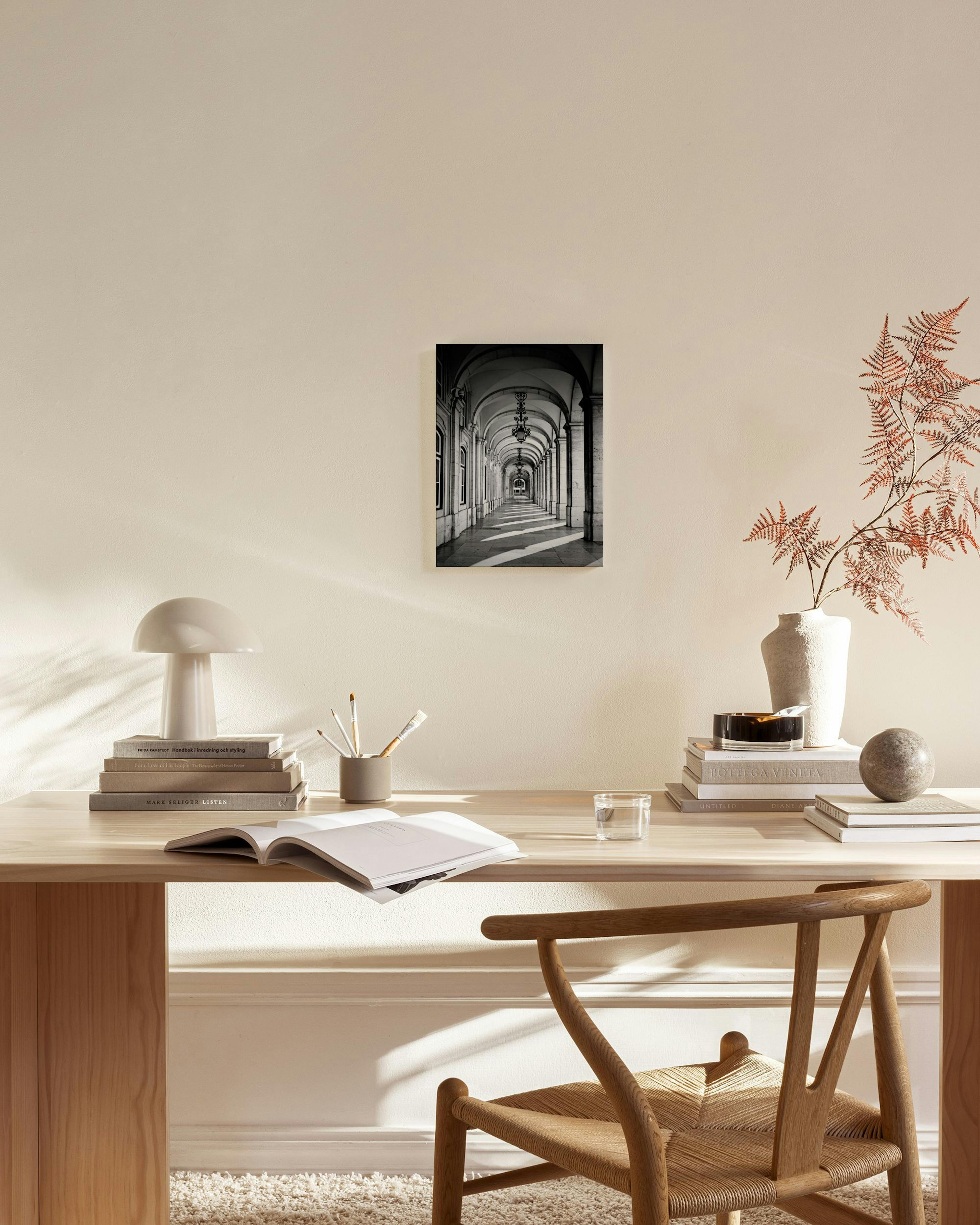 Leinwandbild mit schwarz-weißer Fotografie eines langen Bogengangs mit Licht- und Schattenmustern, über einem Sideboard in einem
