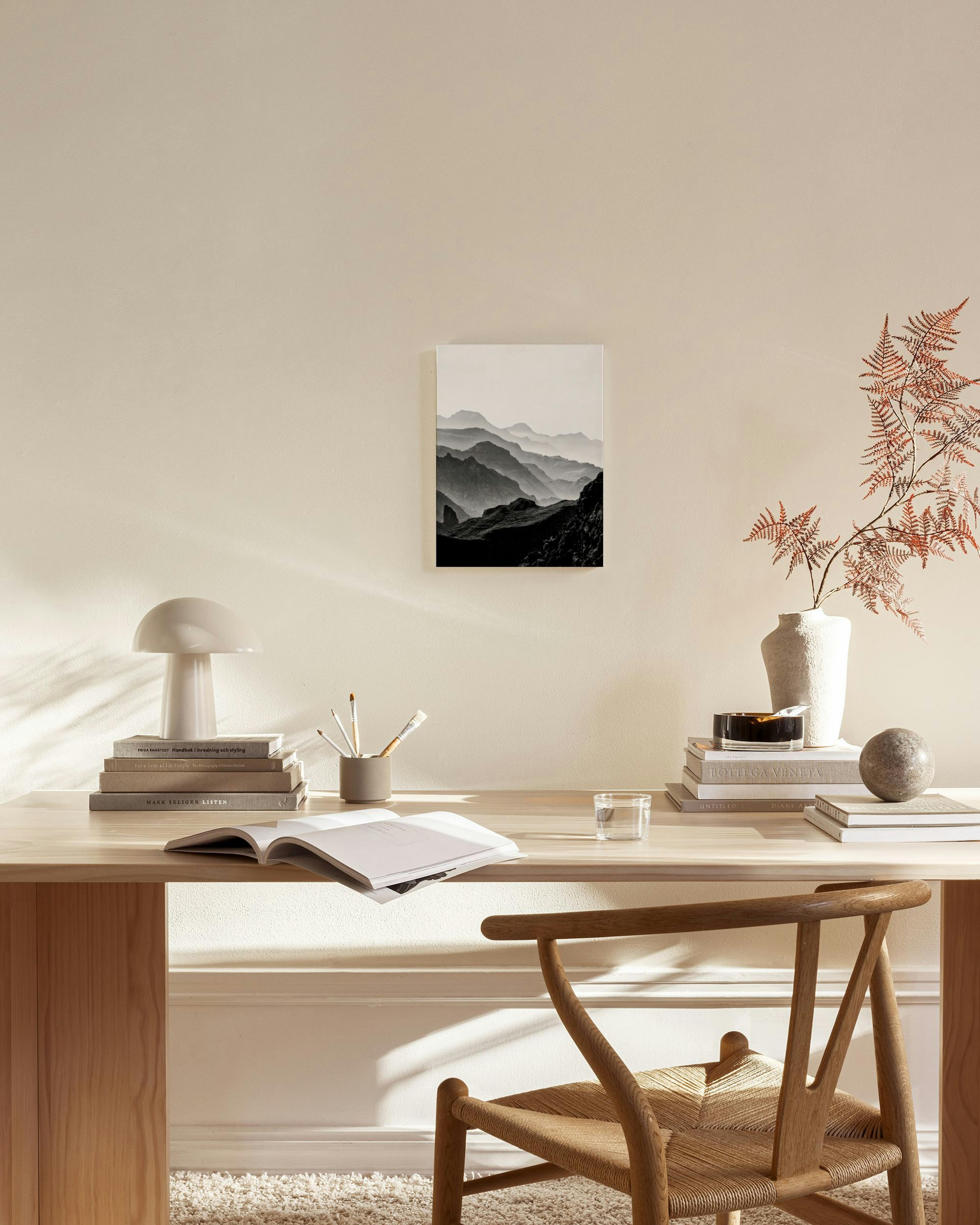 Canvas met zwart-wit foto van bergketens in nevel, hangend in een minimalistische woonkamer.