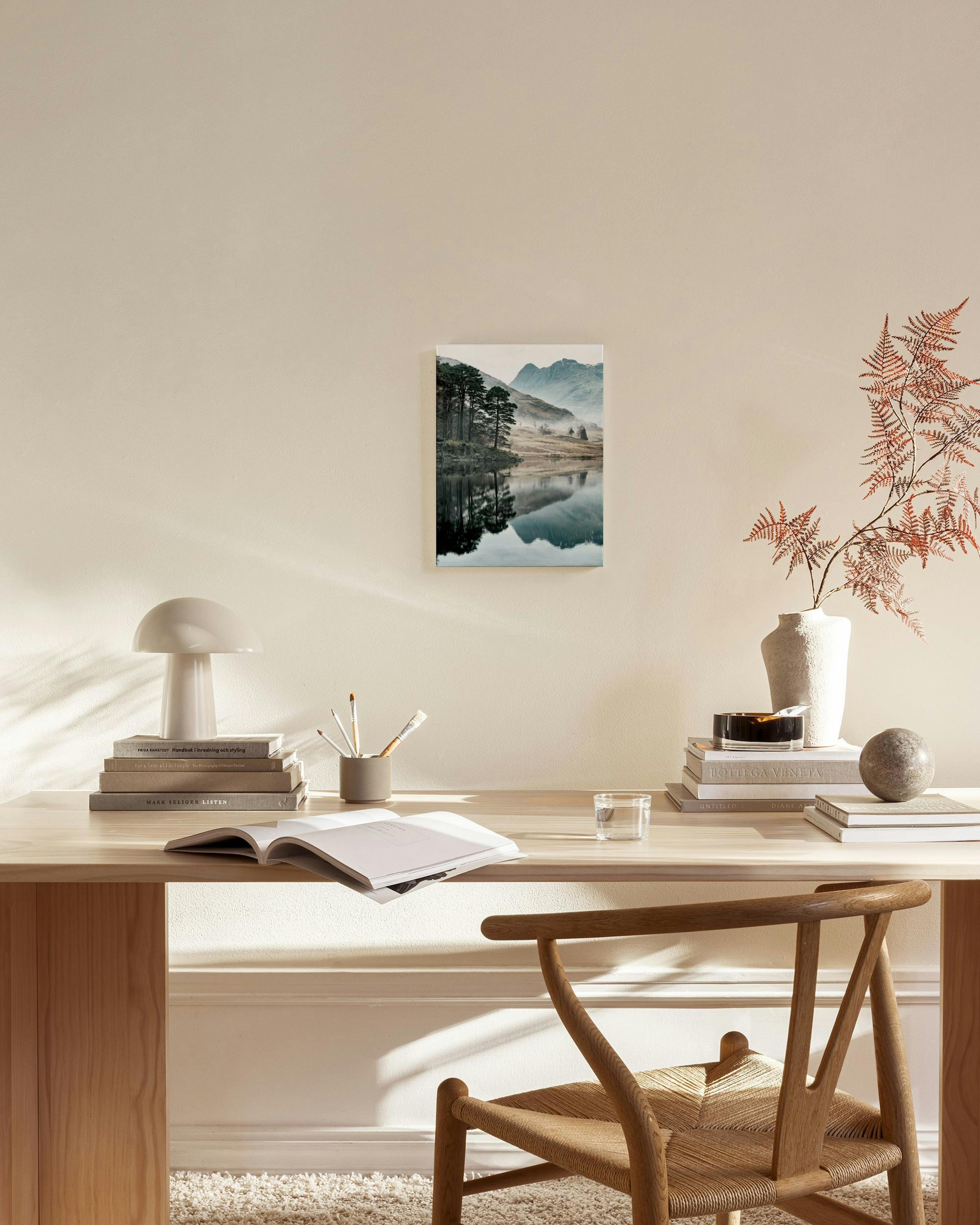 Canvas van een berglandschap met dennenbomen, mist en hun reflectie in het water, hangend in een moderne woonkamer.