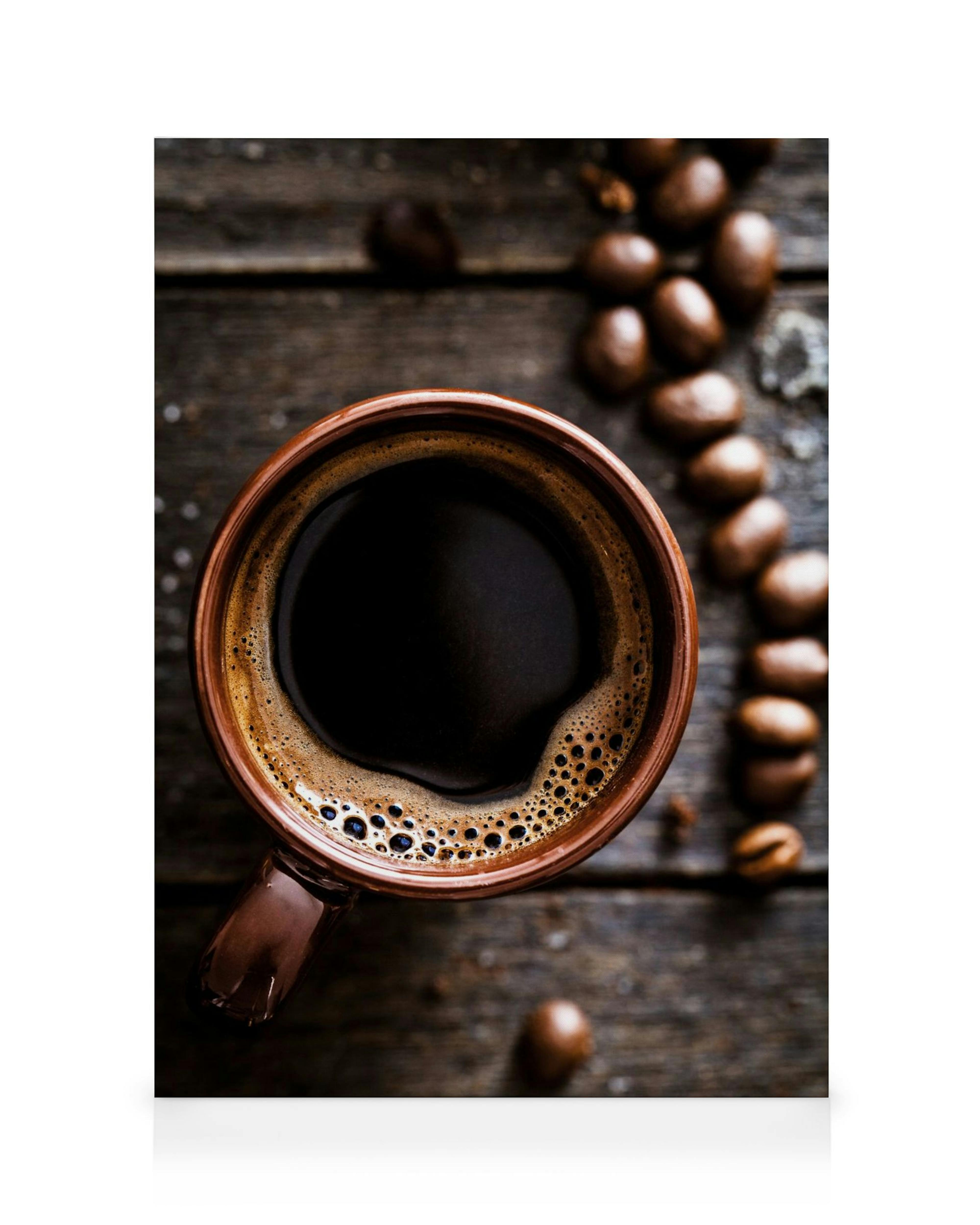 Vista dallalto di una tazza di caffè nero su tavolo di legno scuro, con chicchi di caffè sparsi. Tonalità marroni ricche.