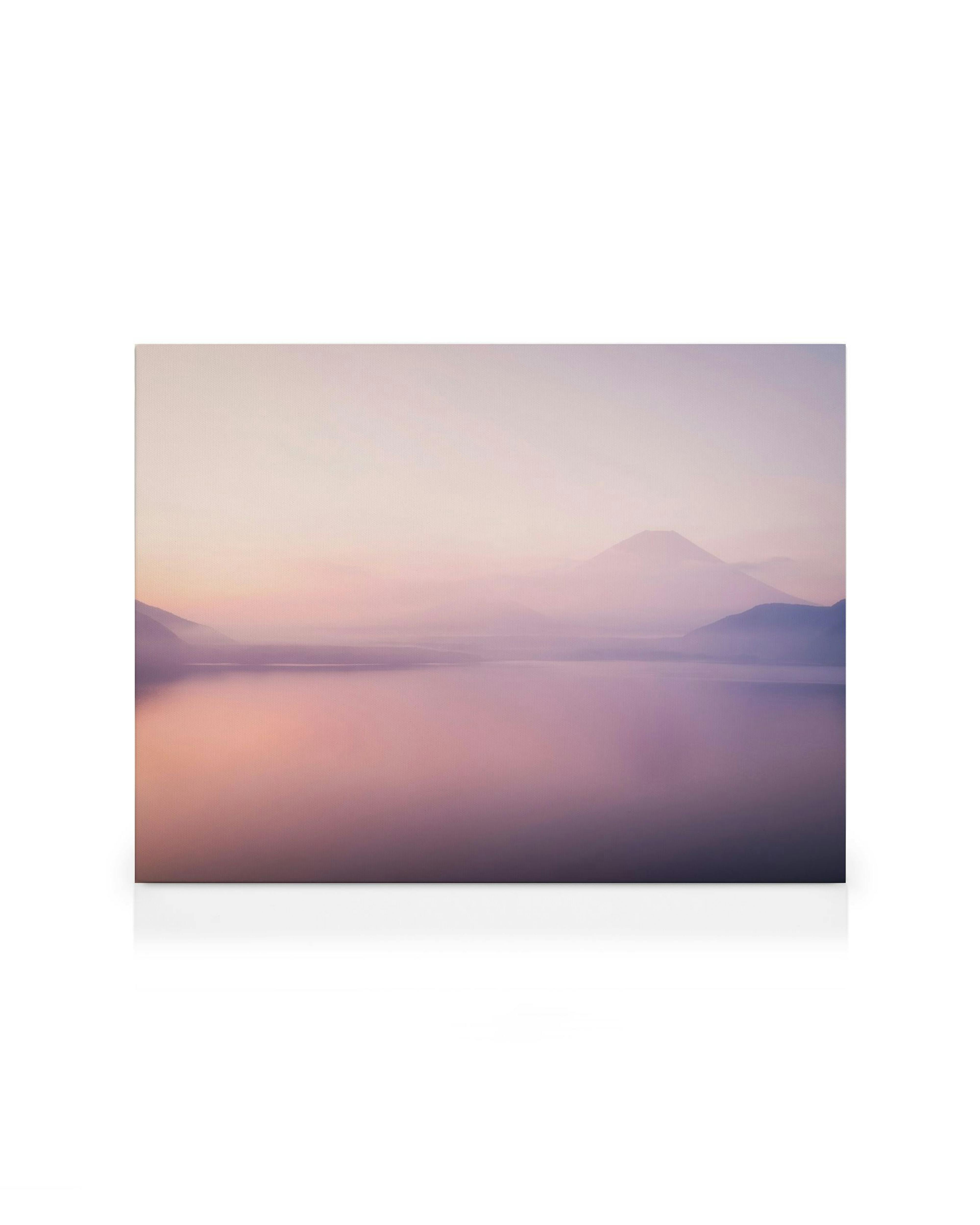 Fuji Mountain over a foggy lake at sunset, with a tranquil pink and purple sky reflecting on the water.