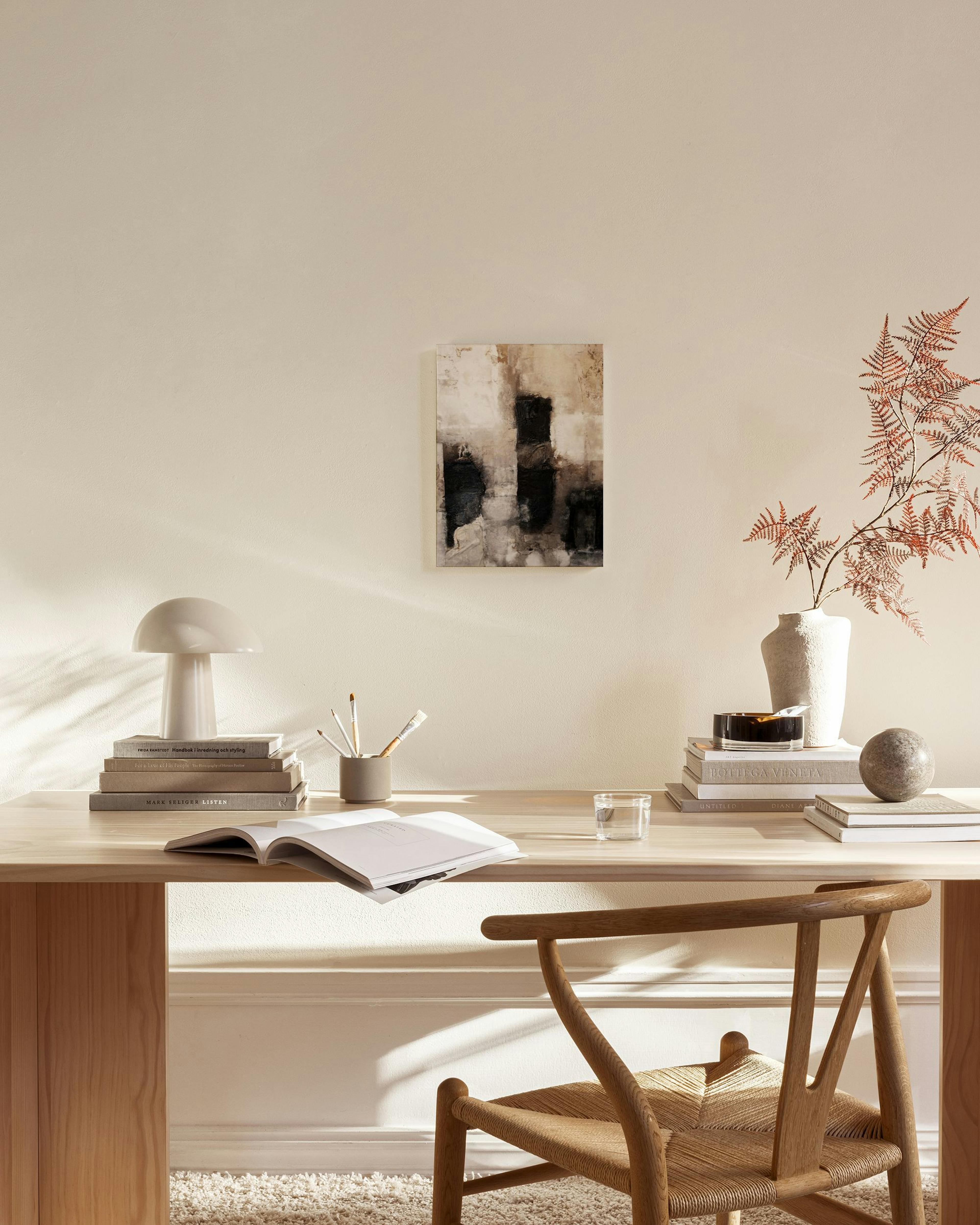 Abstract canvas print with black, beige, and white brushstrokes, hanging in a minimalist living room above a wooden console.