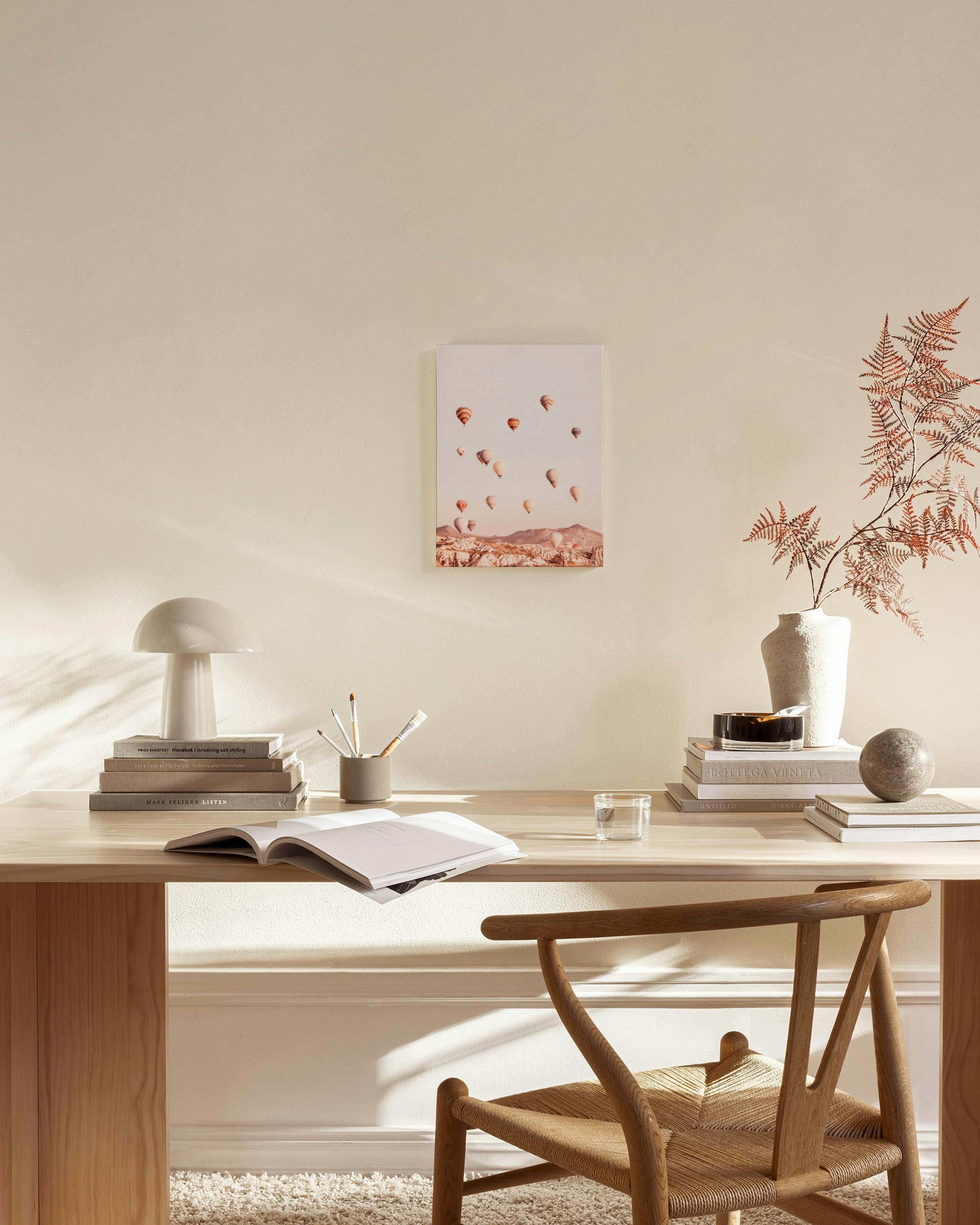 A hot air balloon print over a desert landscape, hanging above a wooden console table in a living room.