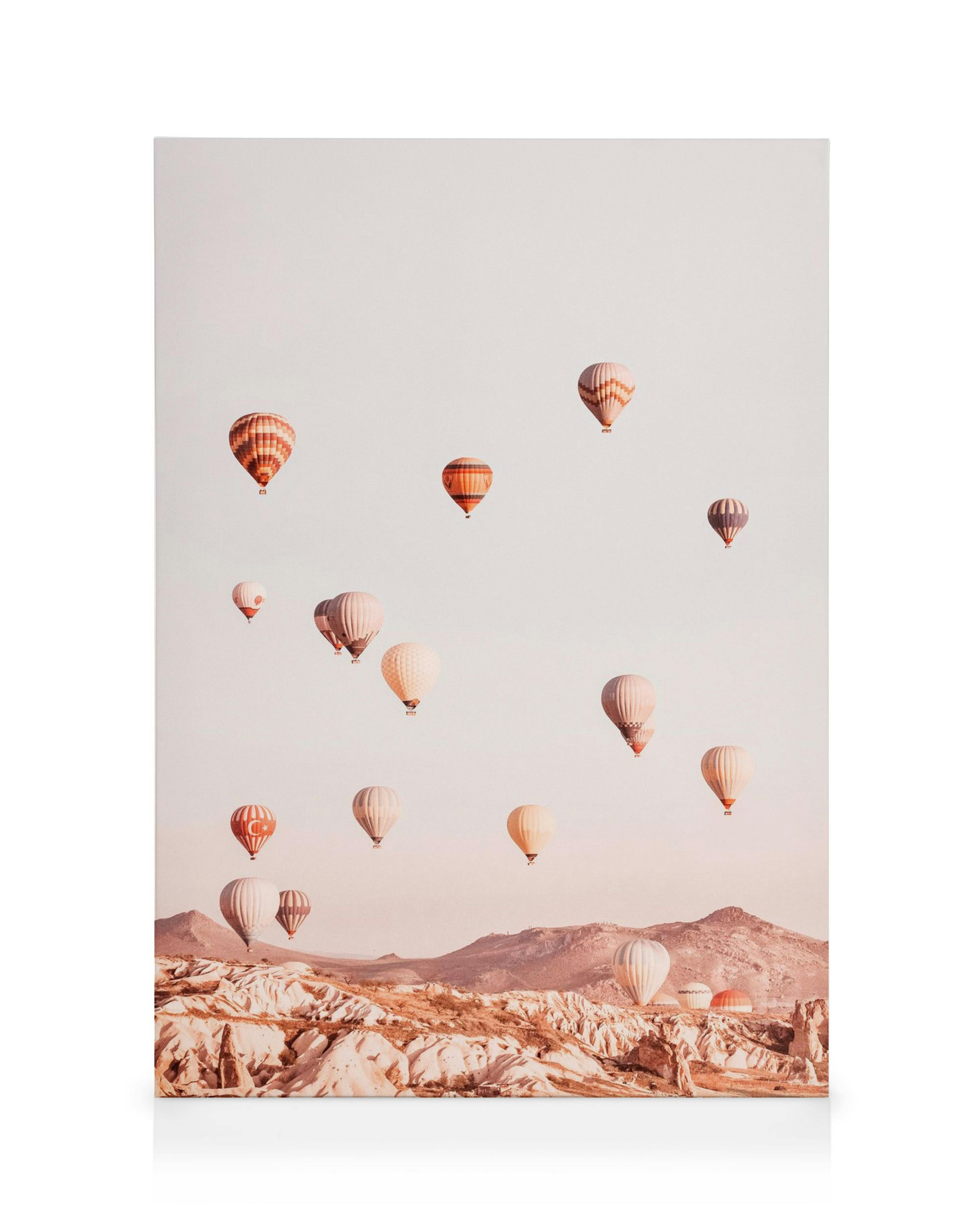 Toile montgolfières colorées flottant dans un ciel orangé au-dessus dun paysage rocheux, ambiance paisible et évasion.