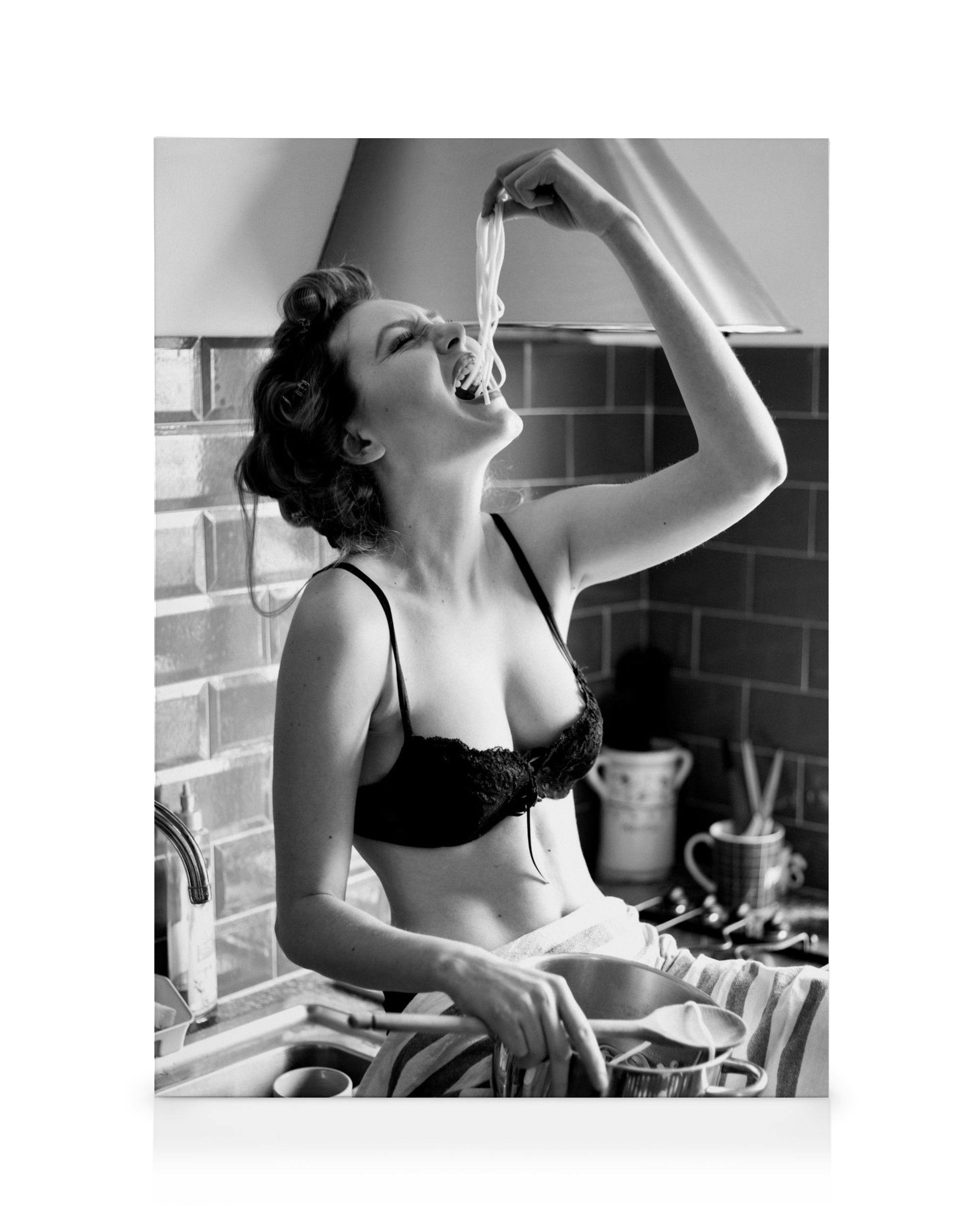 Black and white canvas print of a woman in a bra eating pasta from a pot in a kitchen, Pasta Moment art.