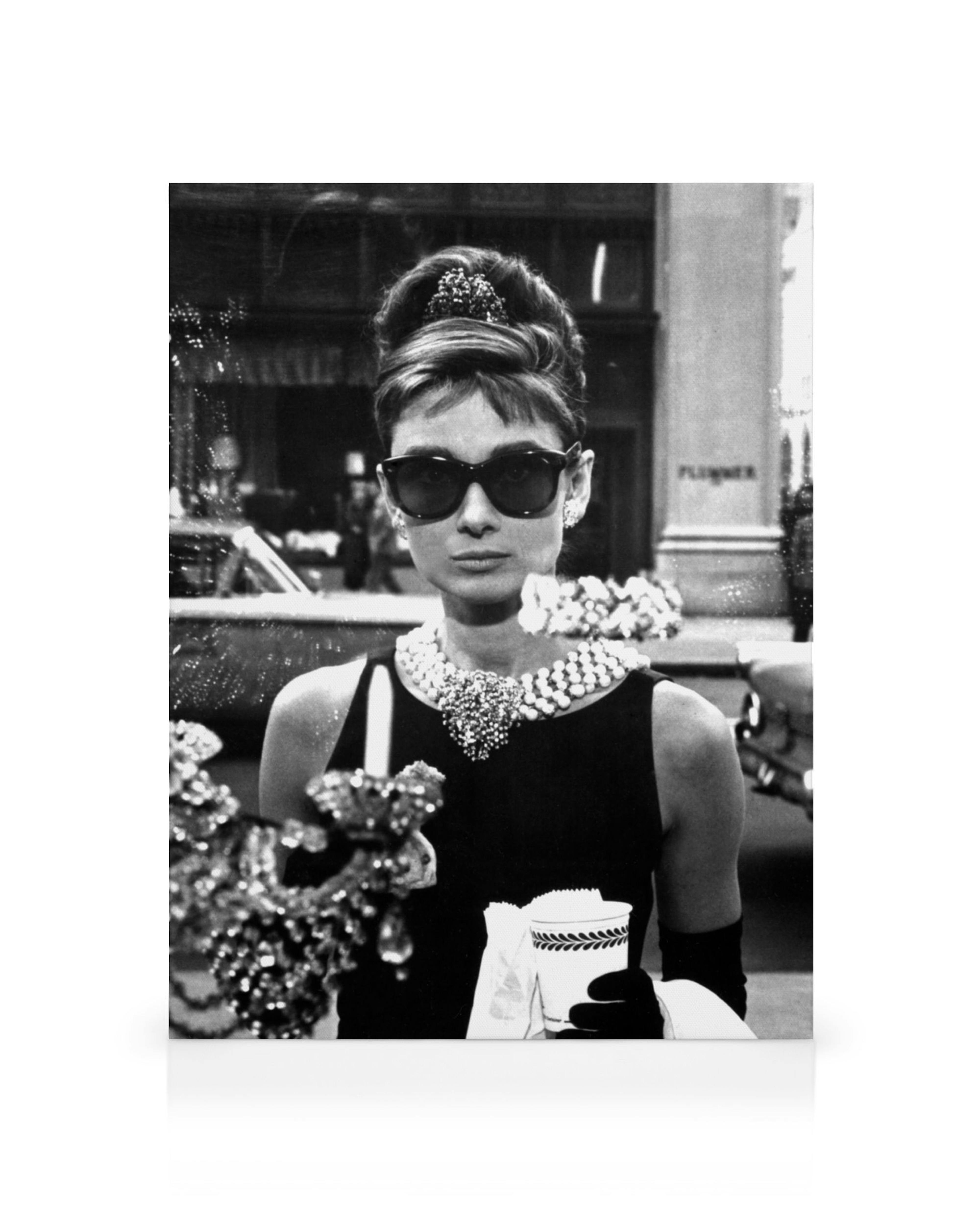 A black and white canvas print featuring Audrey Hepburn in sunglasses and a pearl necklace, holding a cup.
