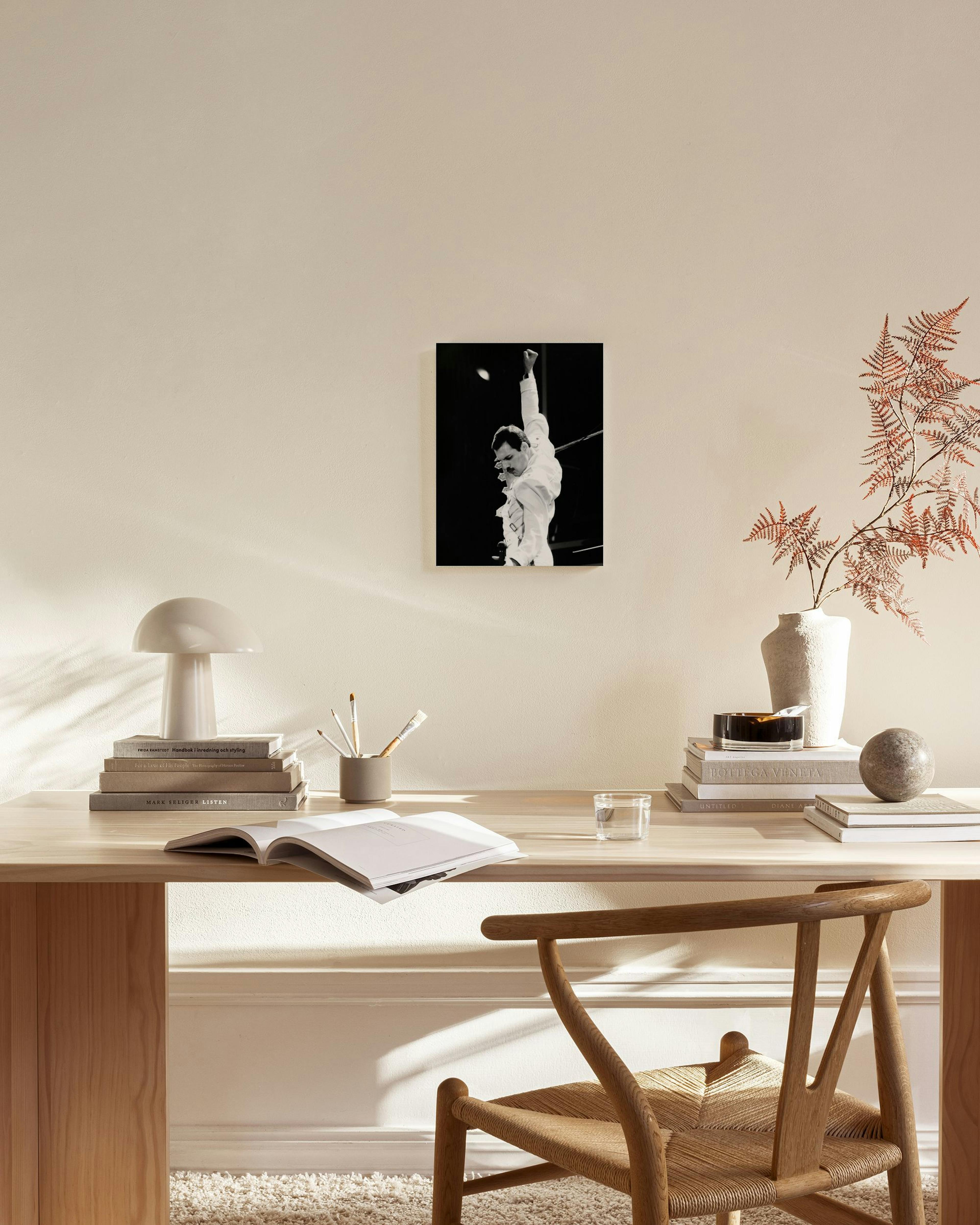 A black and white canvas print of Freddie Mercury with his arm raised, hanging above a wooden console table in a stylish living 