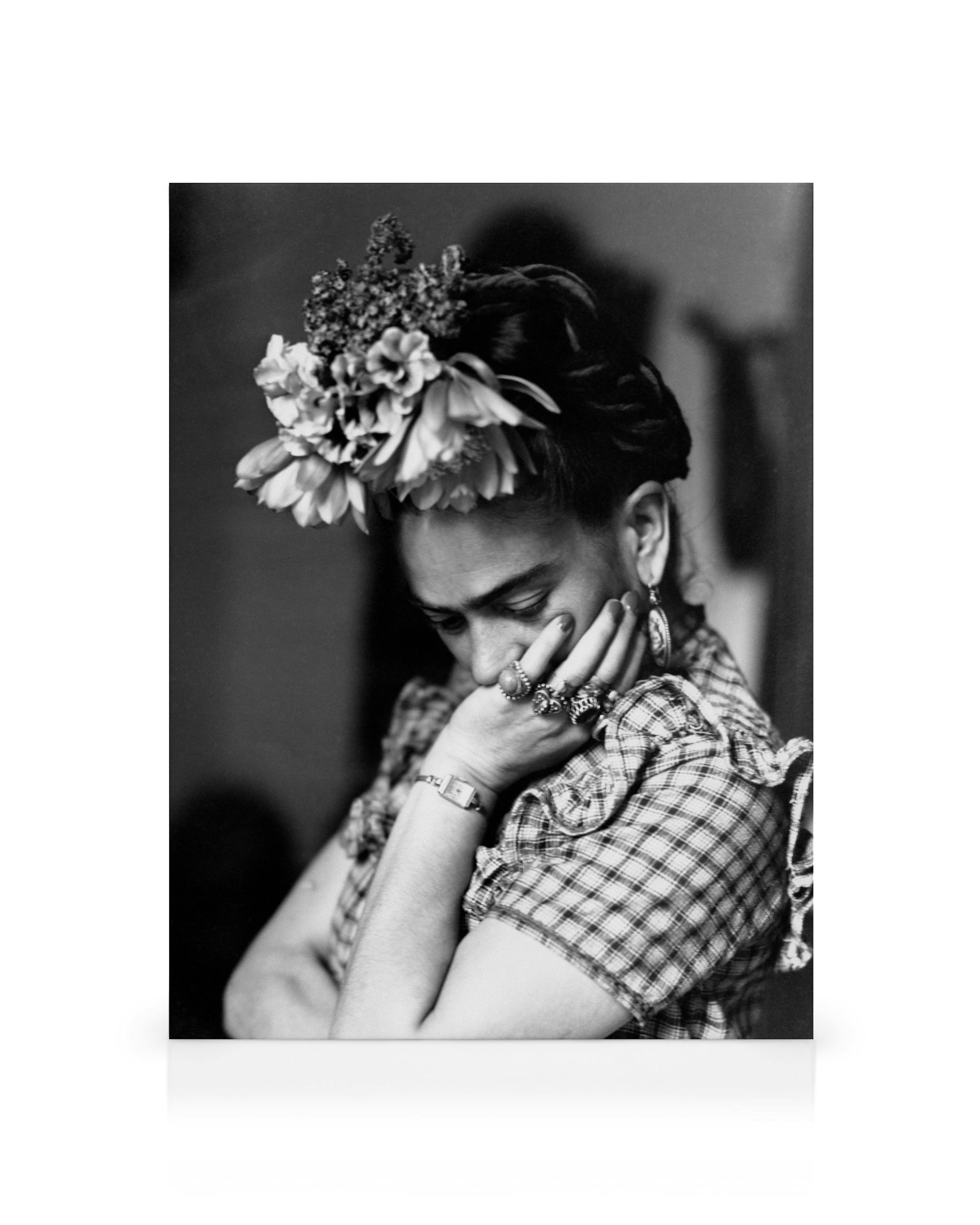 A black and white canvas print of Frida Kahlo with flowers in her hair, resting her chin on her hand.