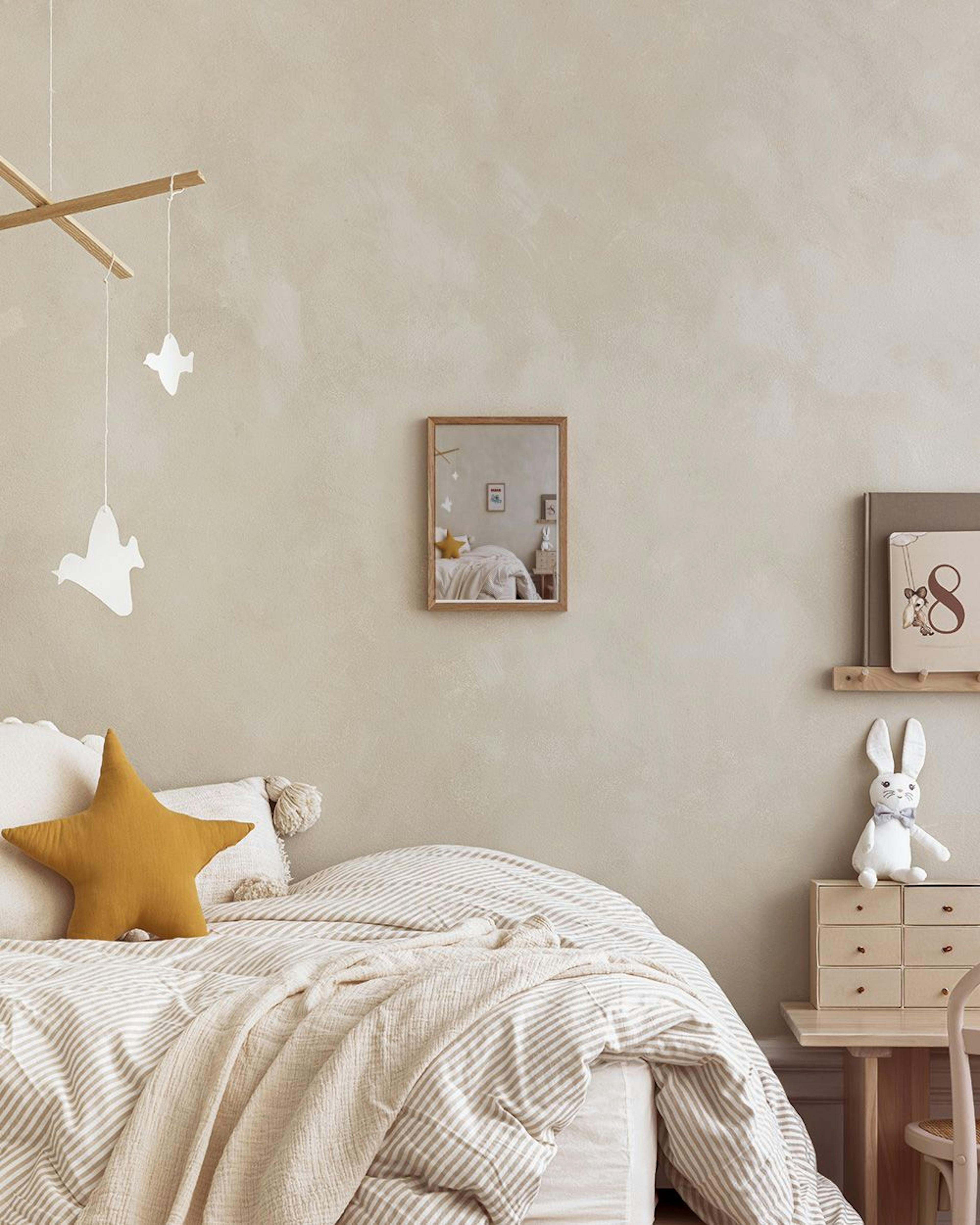 밝은 연두색 벽에 걸린 바바 코끼리 포스터. 바바 코끼리와 가족들이 파란색 자동차를 타고 있는 그림이 있으며, 아래에는 아이 책상과 의자, 디스코볼이 보인다.