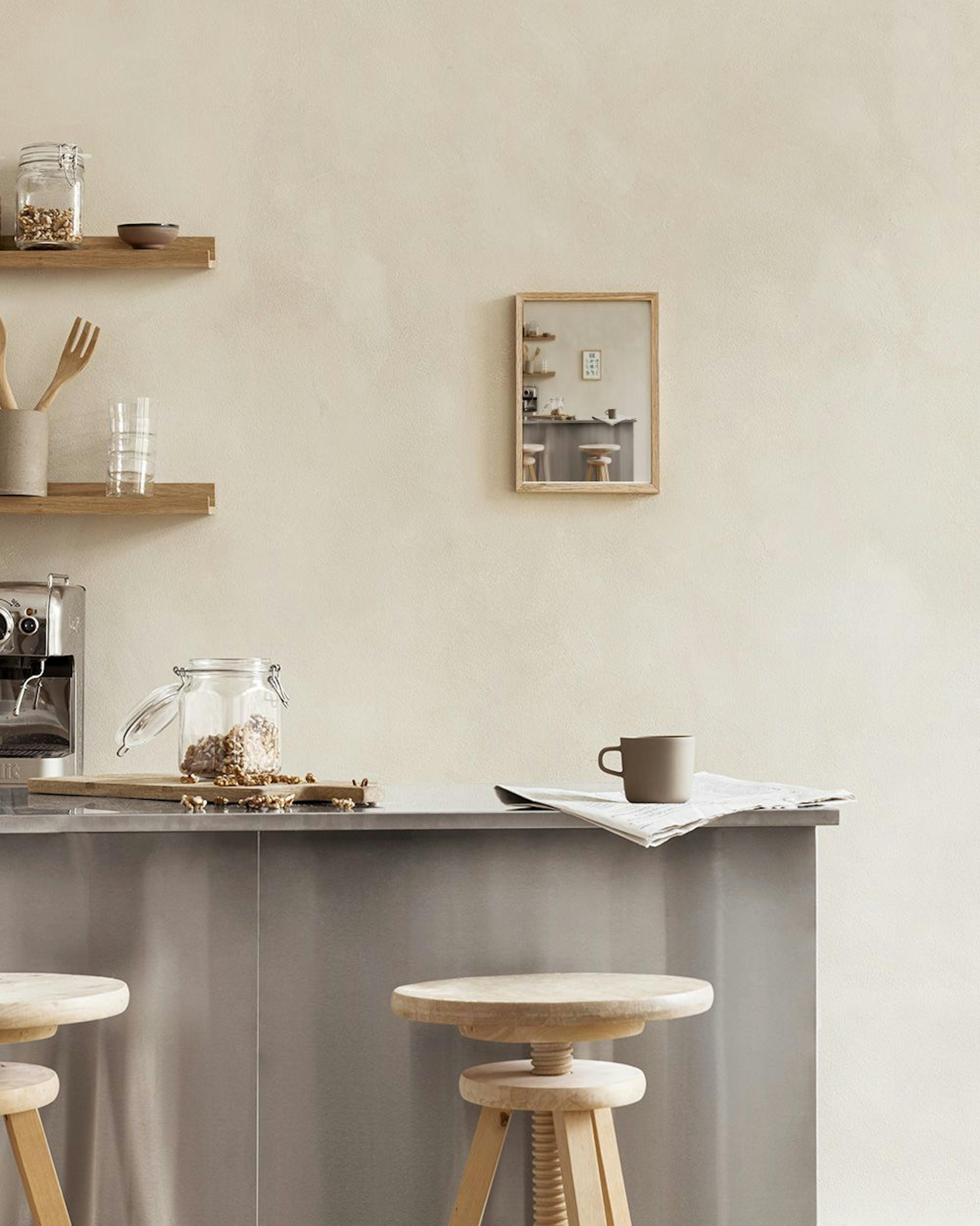 大理石の壁を背景に、キッチンカウンターに飾られたハーブの種類を水彩画で描いたポスター。バジル、ミント、ローズマリーなどが並ぶ。