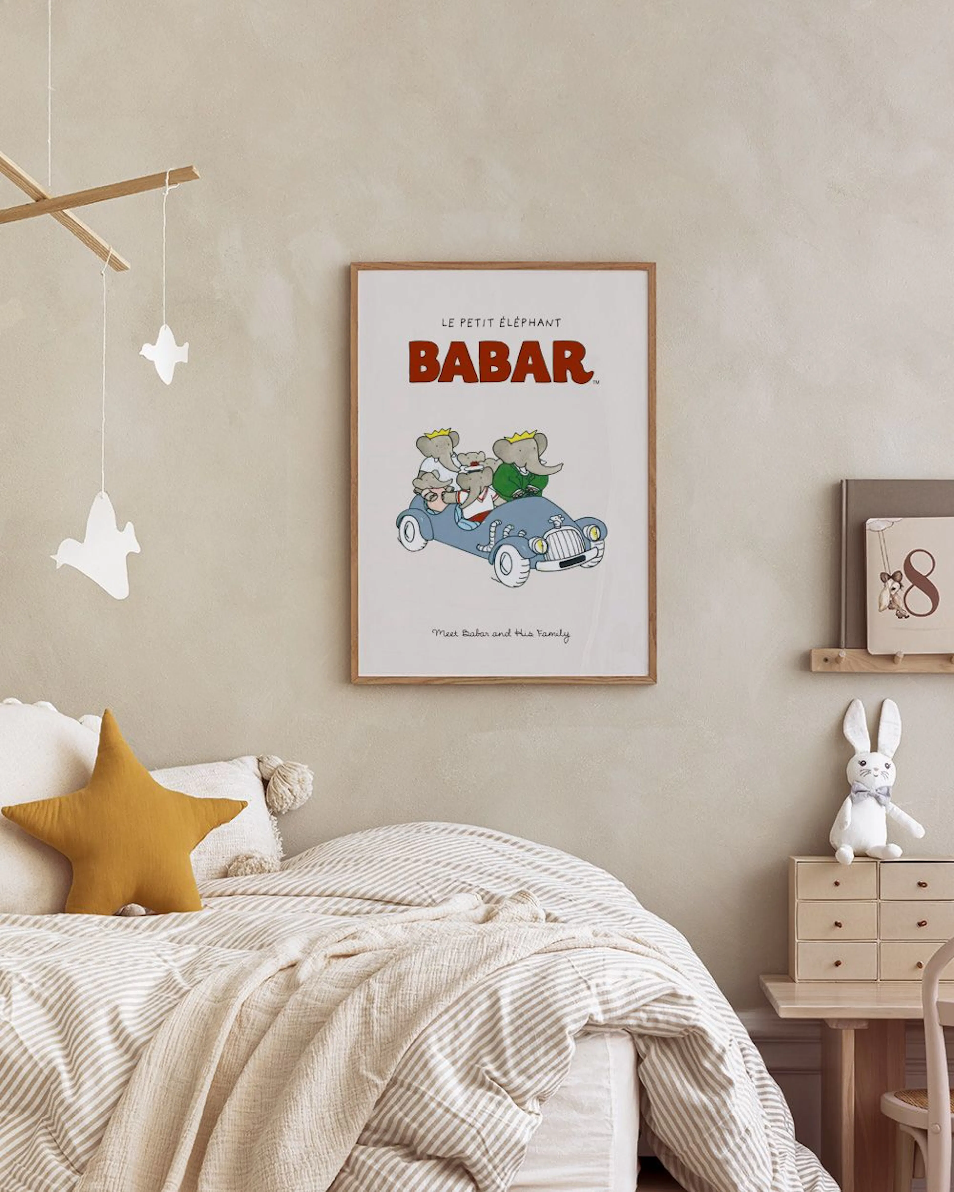 子供部屋の壁に飾られたババールのポスター。ババールと家族が水色の車に乗っているイラストで、机と椅子、積み木が周りにある。