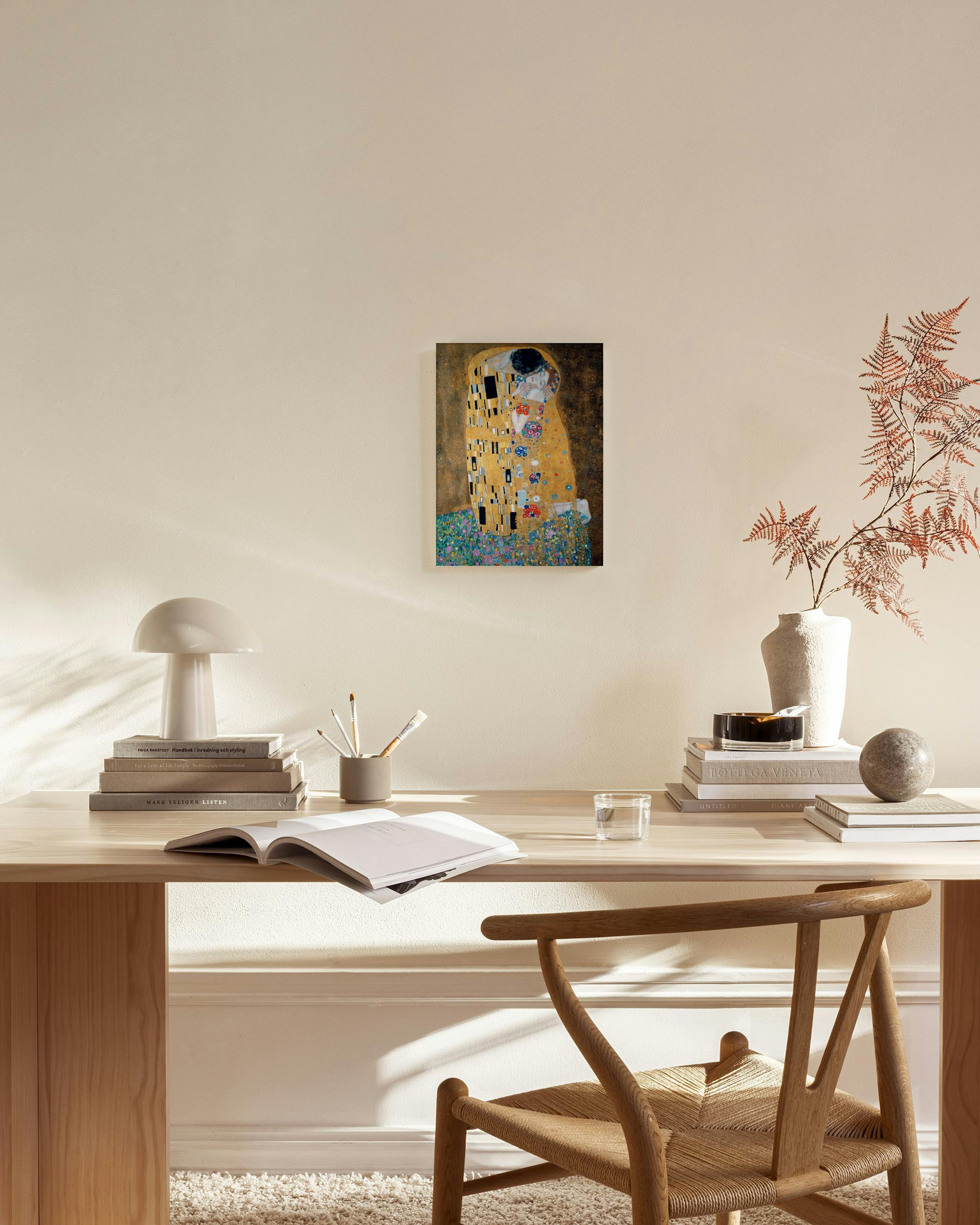 Canvastavla av Klimts Kyssen med ett par i gulddetaljer, hängande i ett modernt vardagsrum ovanför en bänk.