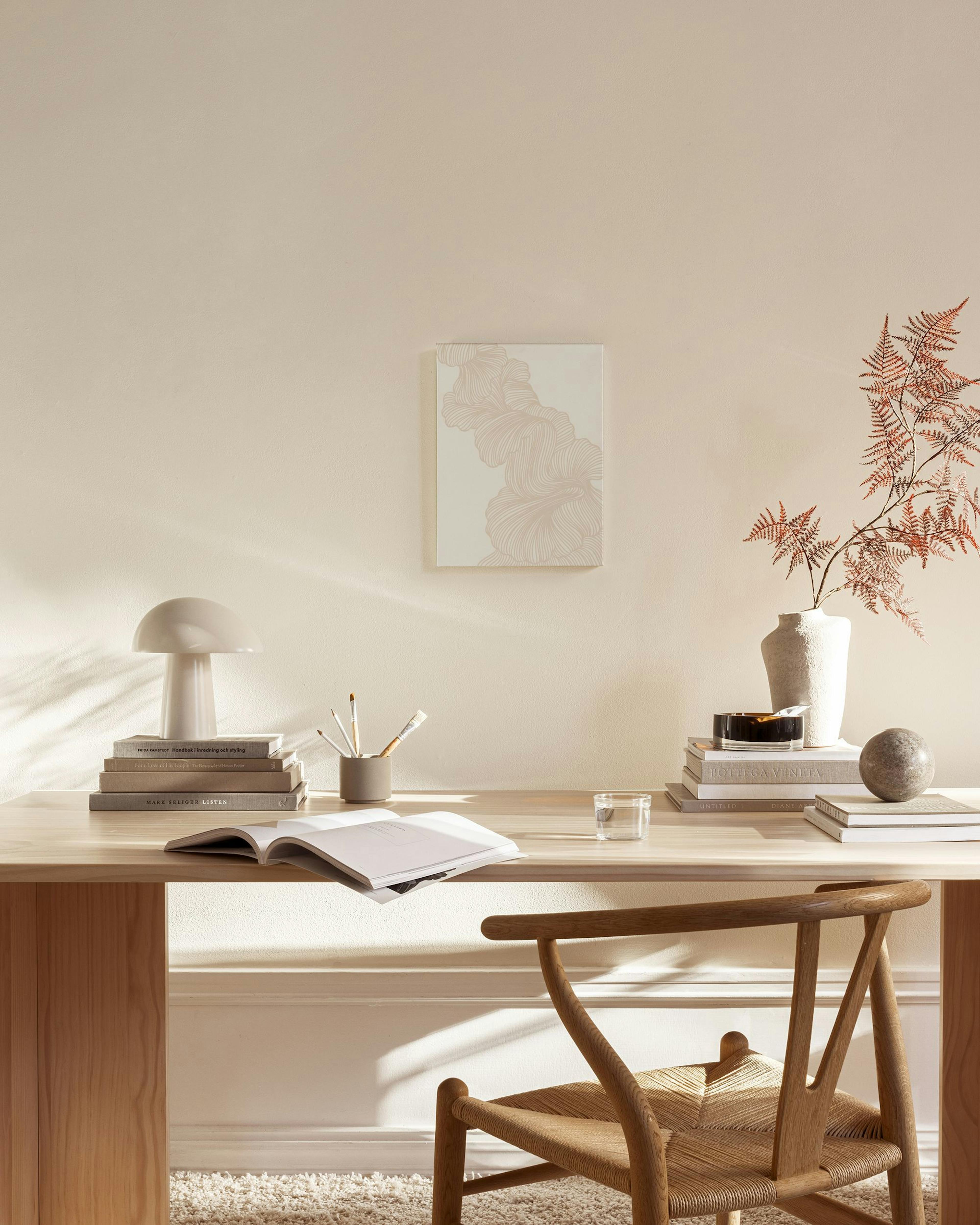 An abstract print featuring flowing beige and white organic lines, displayed in a minimalist living room above a wooden console.