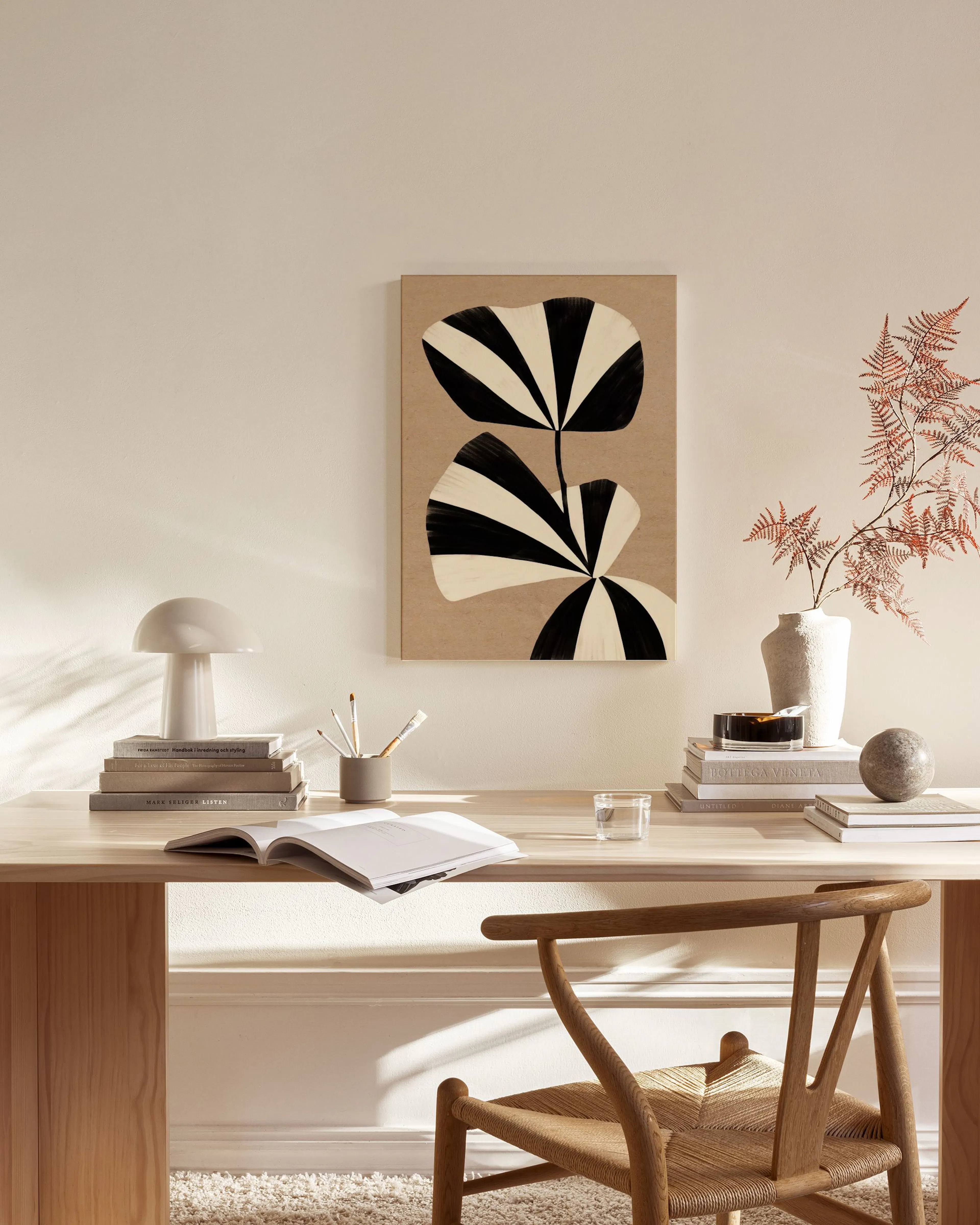 A canvas print with black and white striped organic shapes on a brown background, displayed in a light-filled living room.