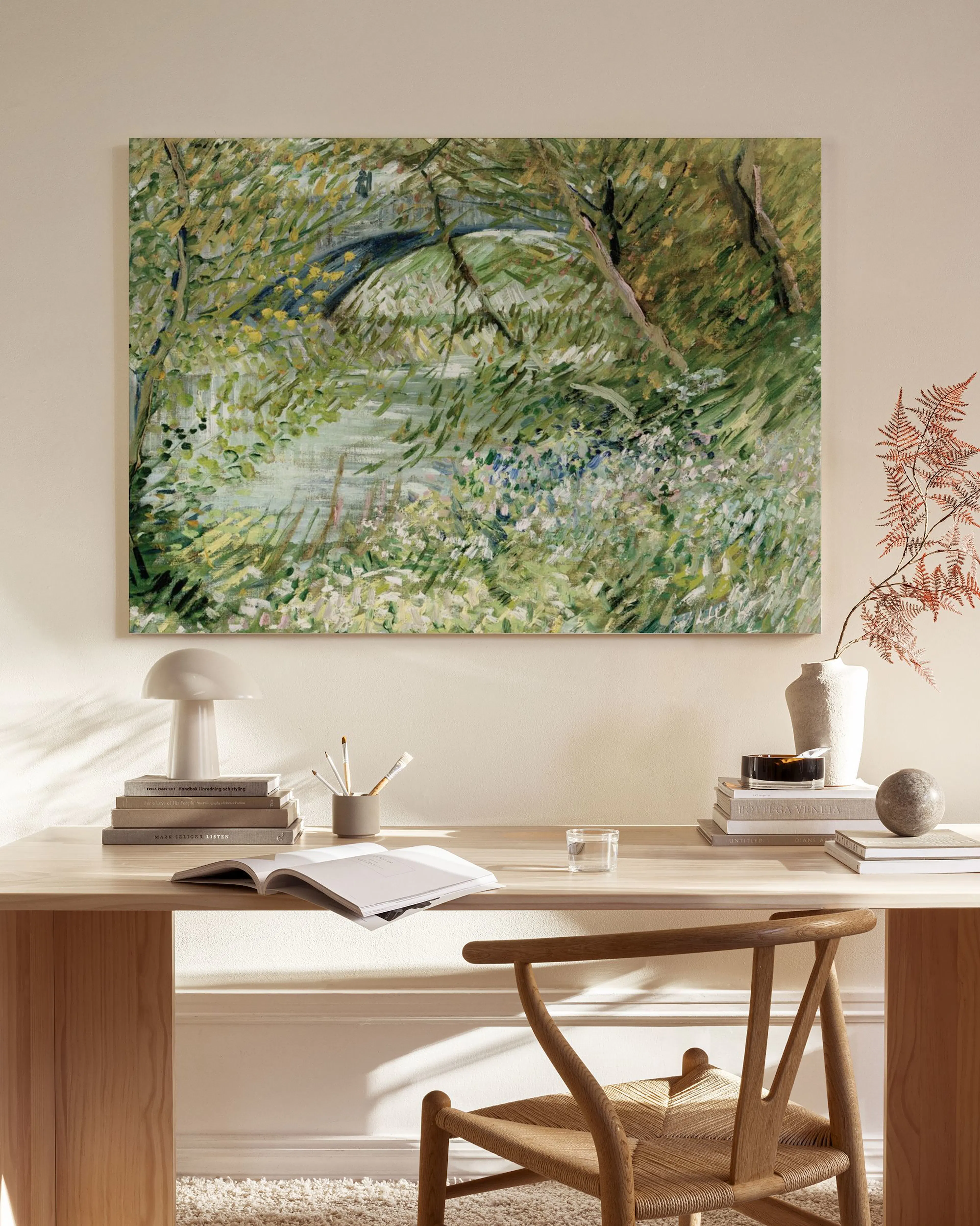 Impressionist landscape canvas print depicting a bridge over a lush, green stream, hanging in a modern living room.