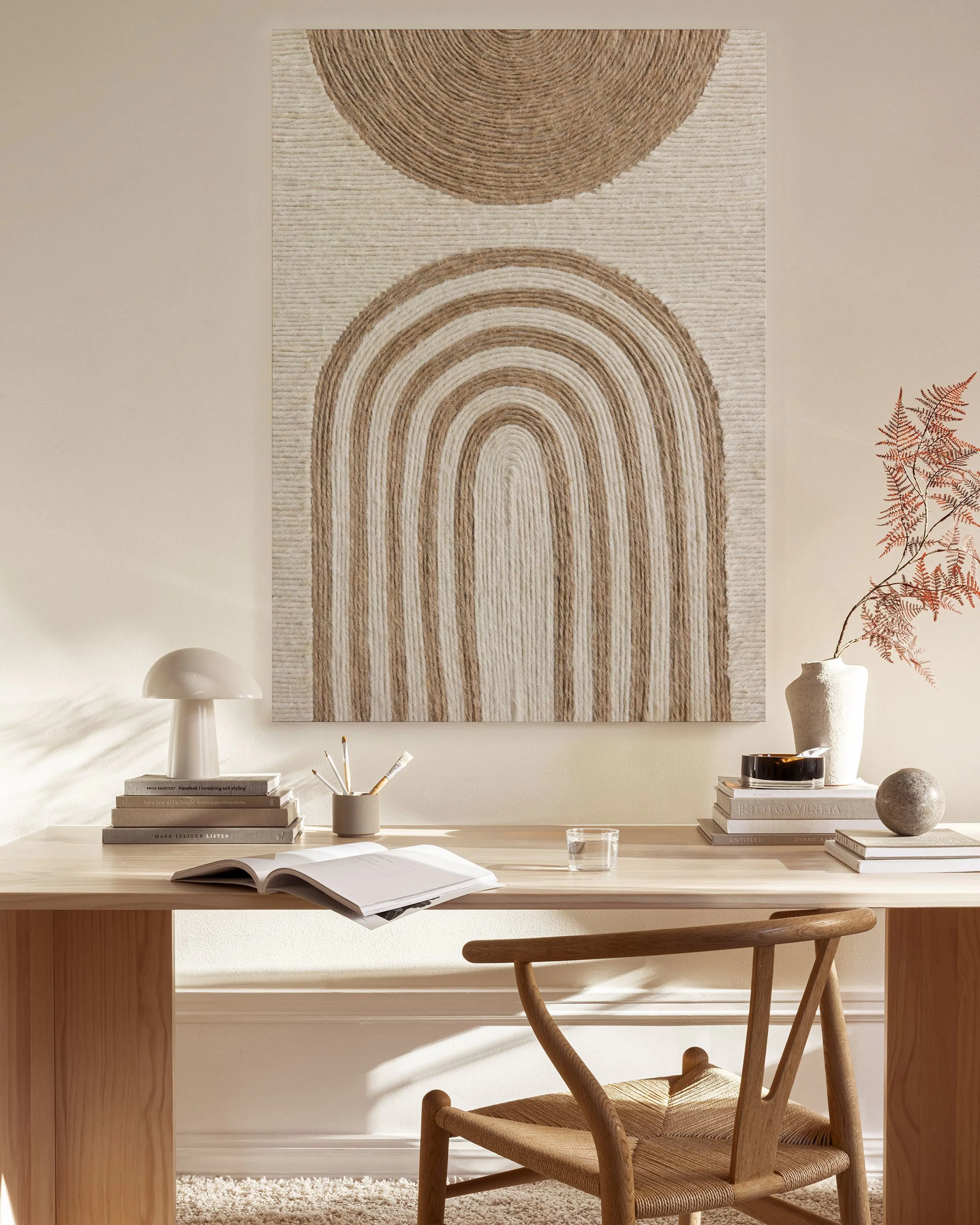 Toile murale beige et marron avec un demi-cercle au-dessus de formes arquées, suspendue dans un salon moderne.