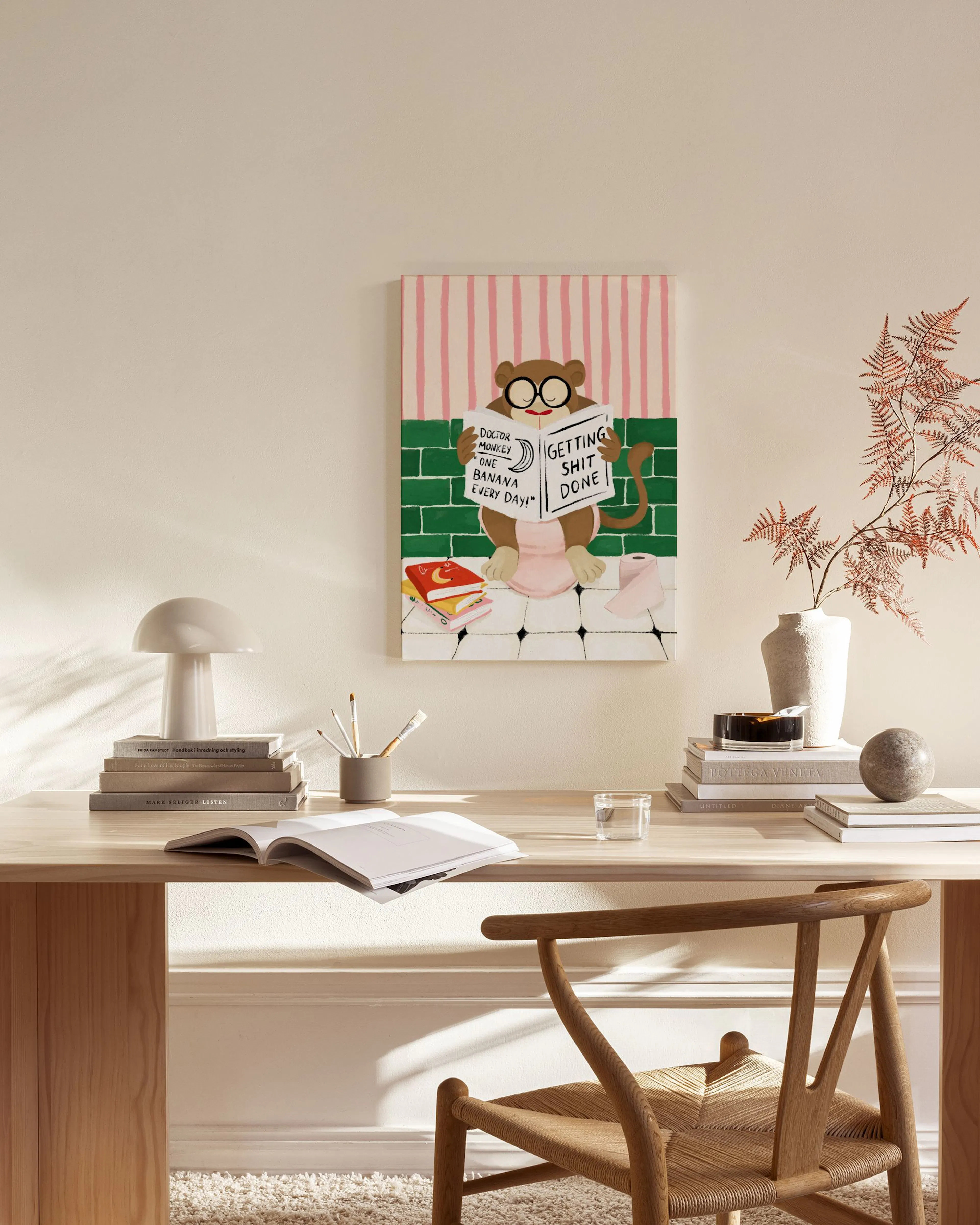 Lienzo de un mono leyendo un libro, con fondo de rayas rosas y azulejos verdes, colgado en una sala de estar moderna.