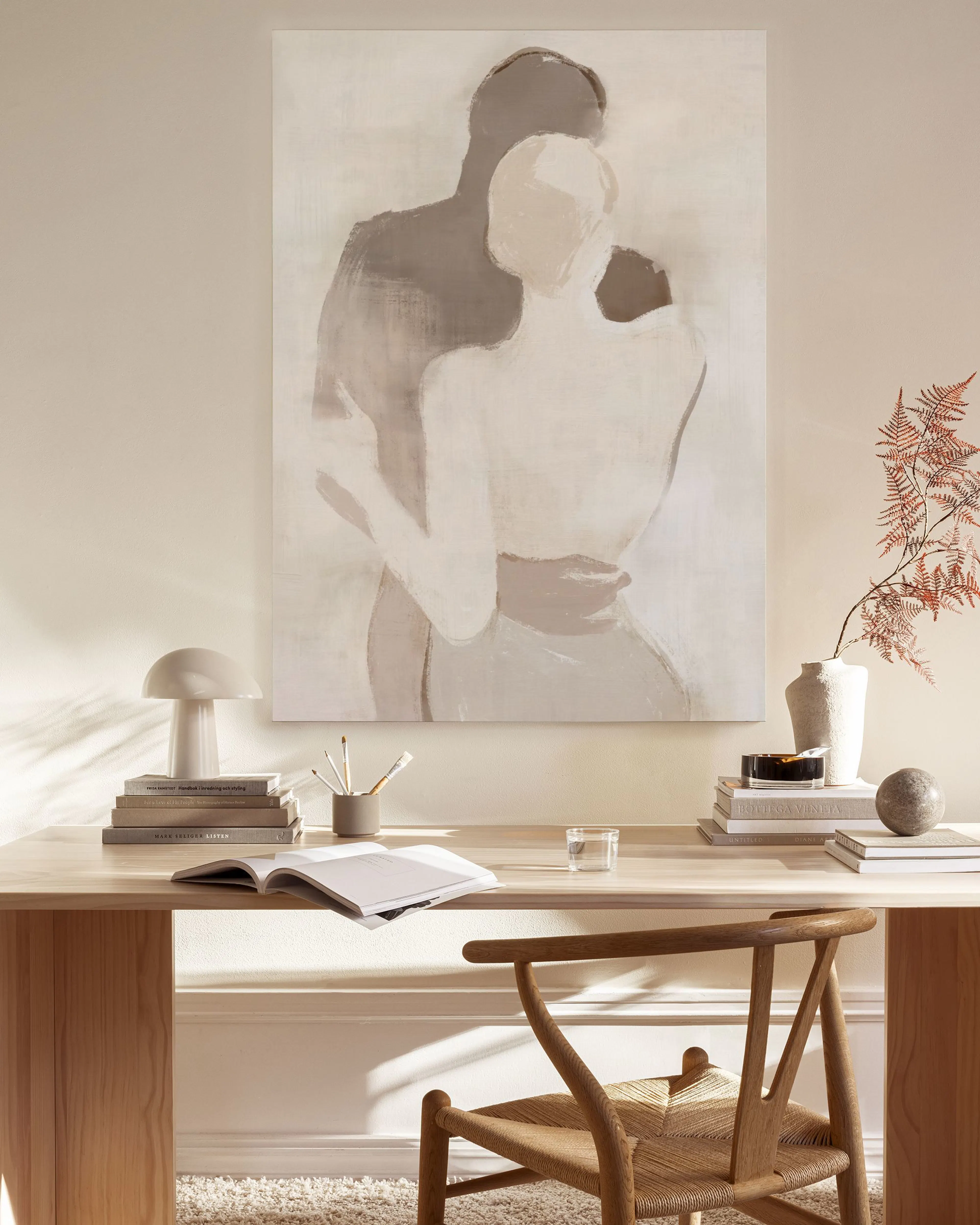 Canvas van twee omhelzende figuren in neutrale tinten, hangend boven een tv-meubel in een moderne woonkamer.