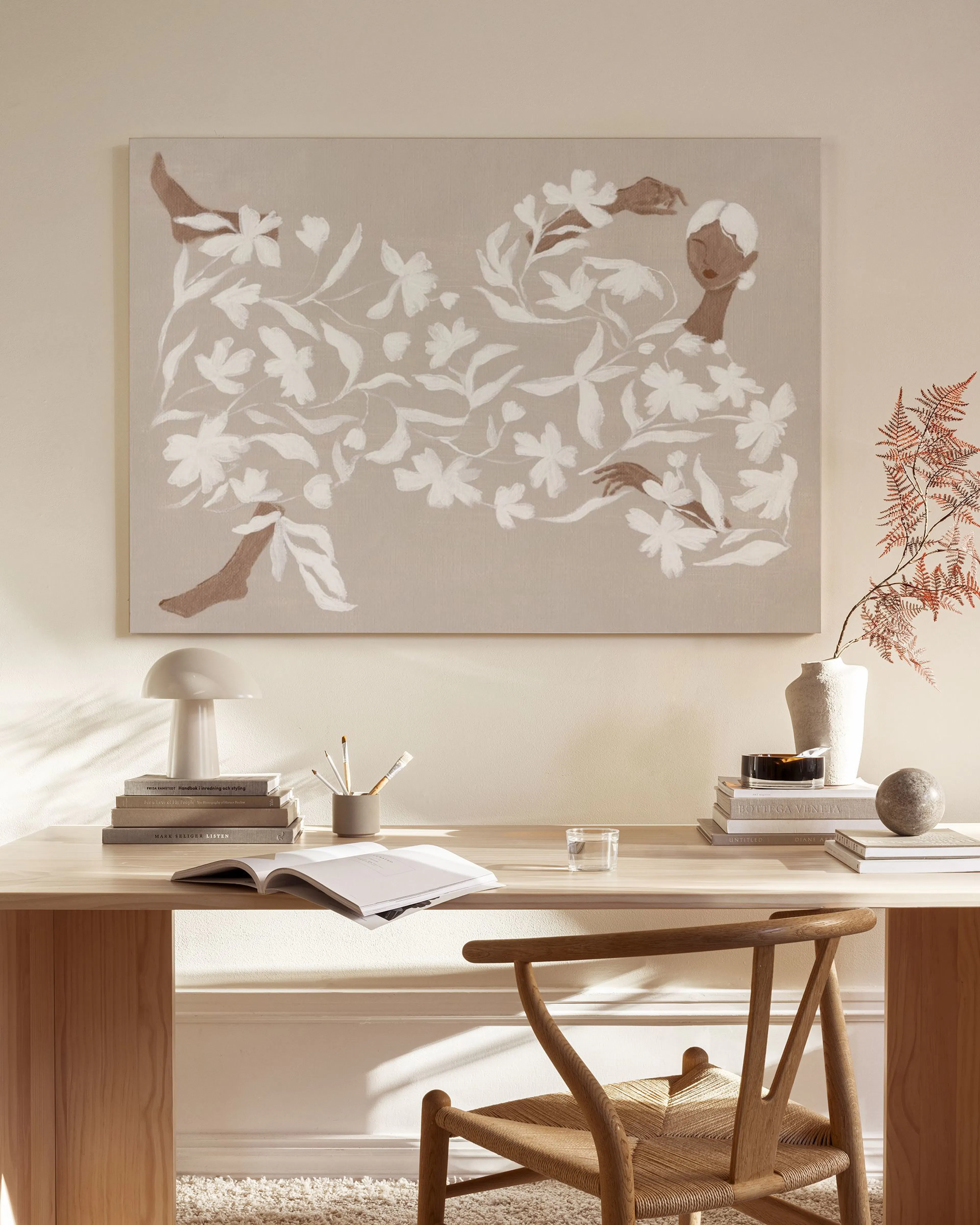 Lerretsbilde med abstrakt blomstermønster og mørke hender/føtter på beige bakgrunn, henger over en trefarget benk i en moderne s