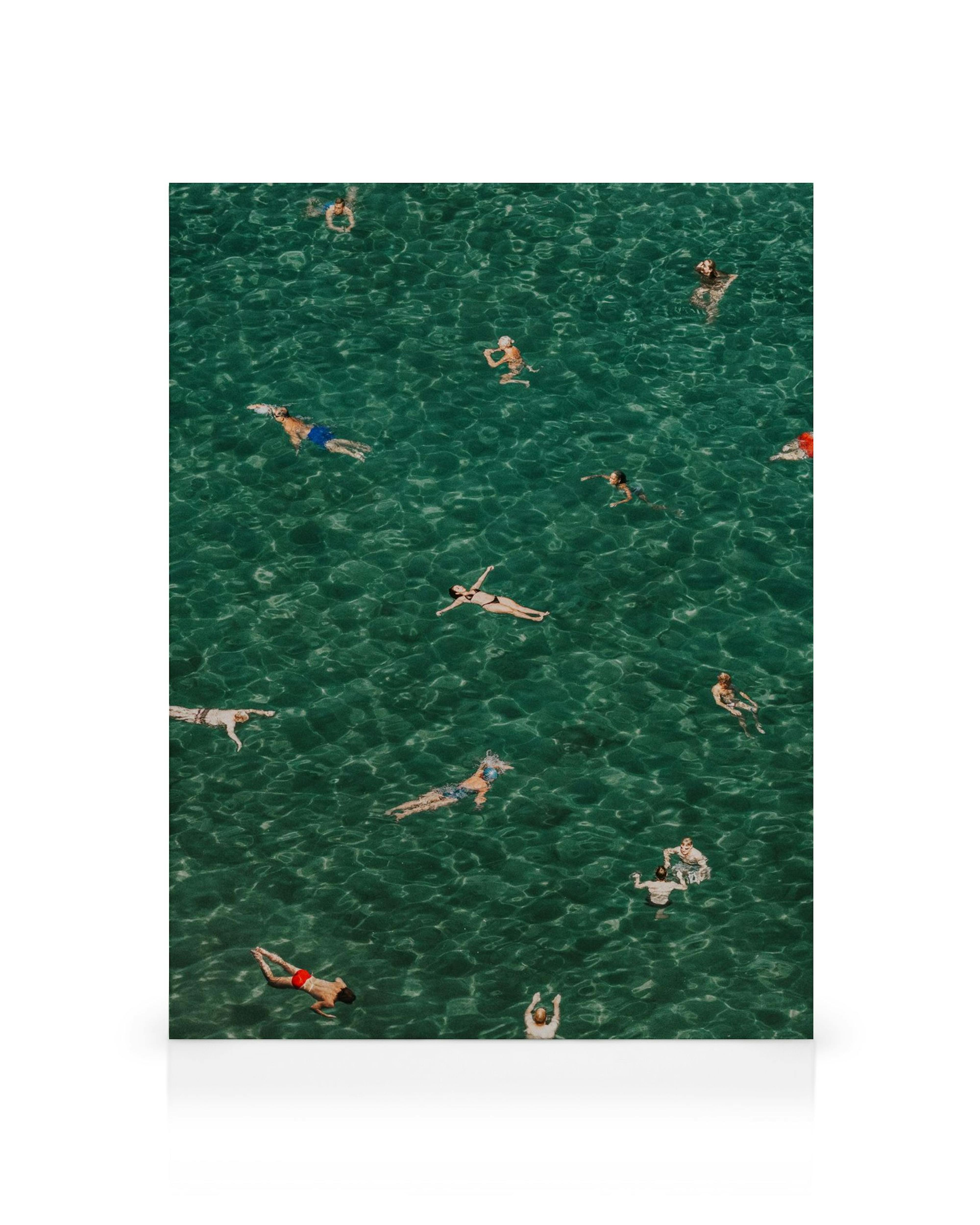 Fotografía aérea de personas flotando en agua turquesa, creando un ambiente veraniego y relajante.