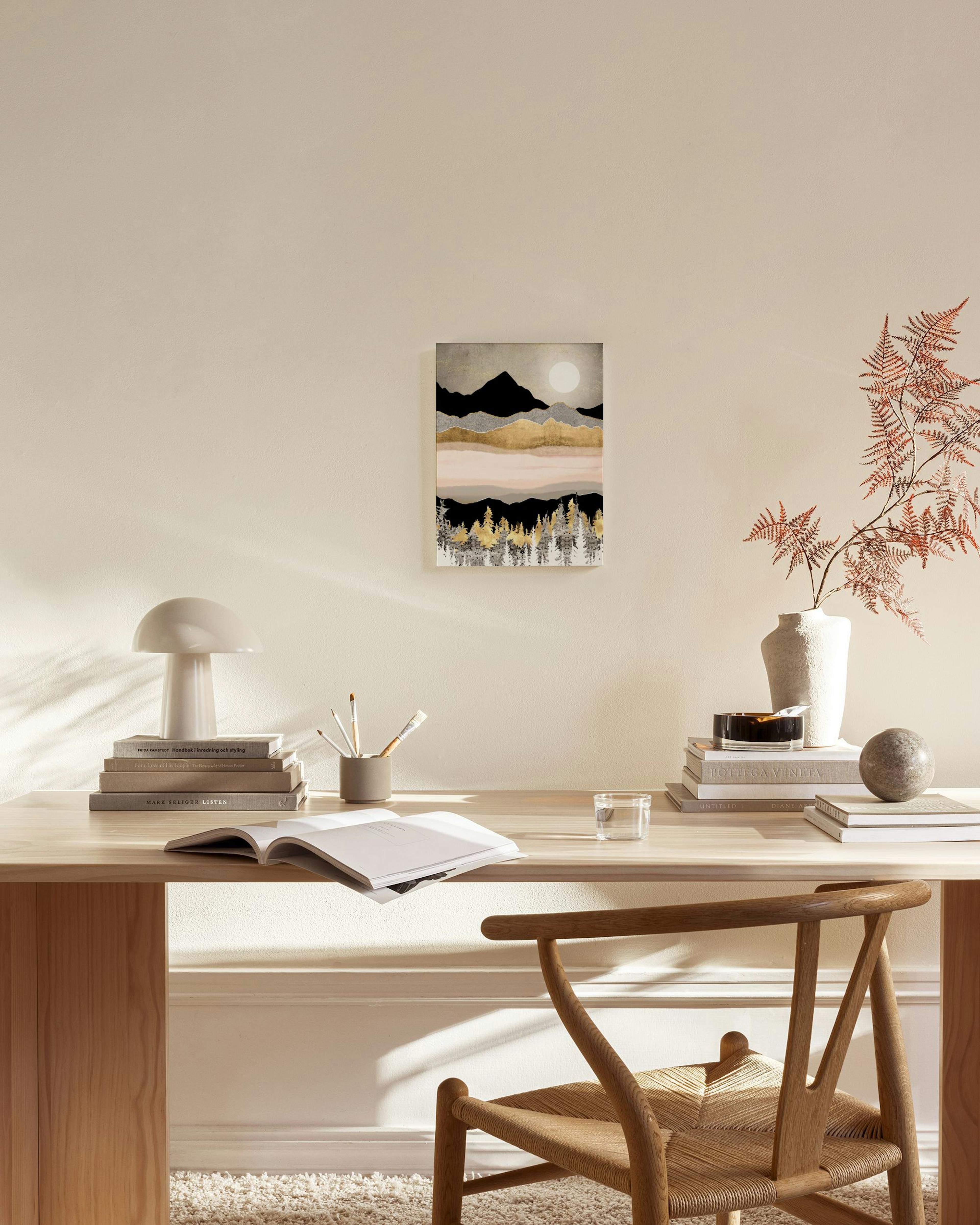 Toile murale de paysage de montagnes et forêt aux teintes dorées et noires, accrochée dans un salon moderne.